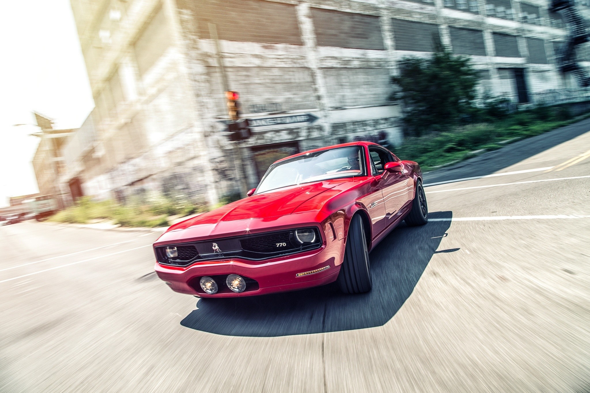 Red classic muscle car driving on a city street HD Wallpaper