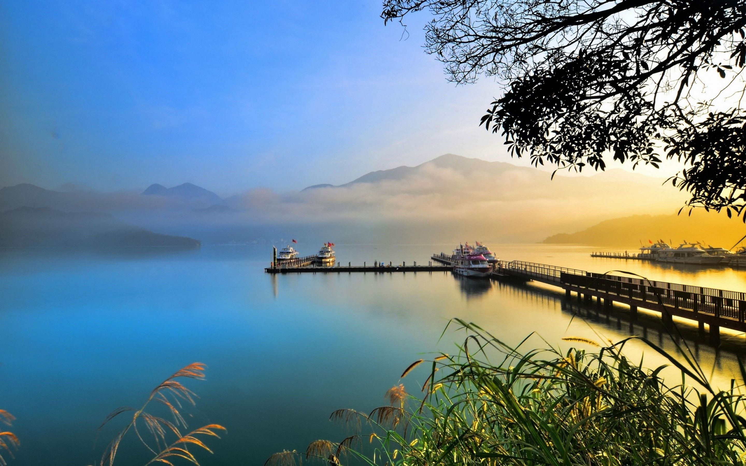 Boats docked at a pier on a misty lake at sunrise HD Wallpaper