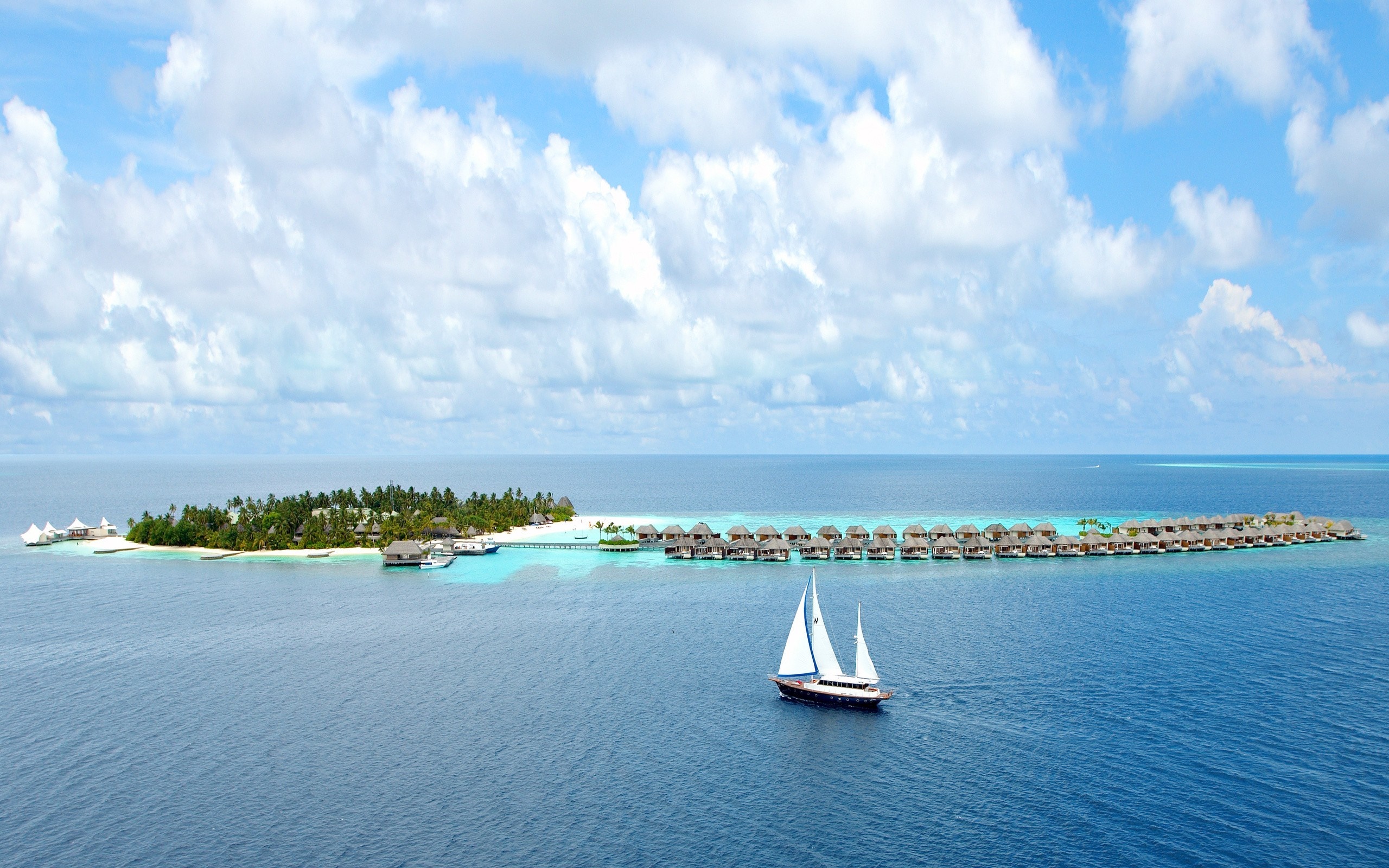 Sailboat near tropical islands with overwater bungalows HD Wallpaper