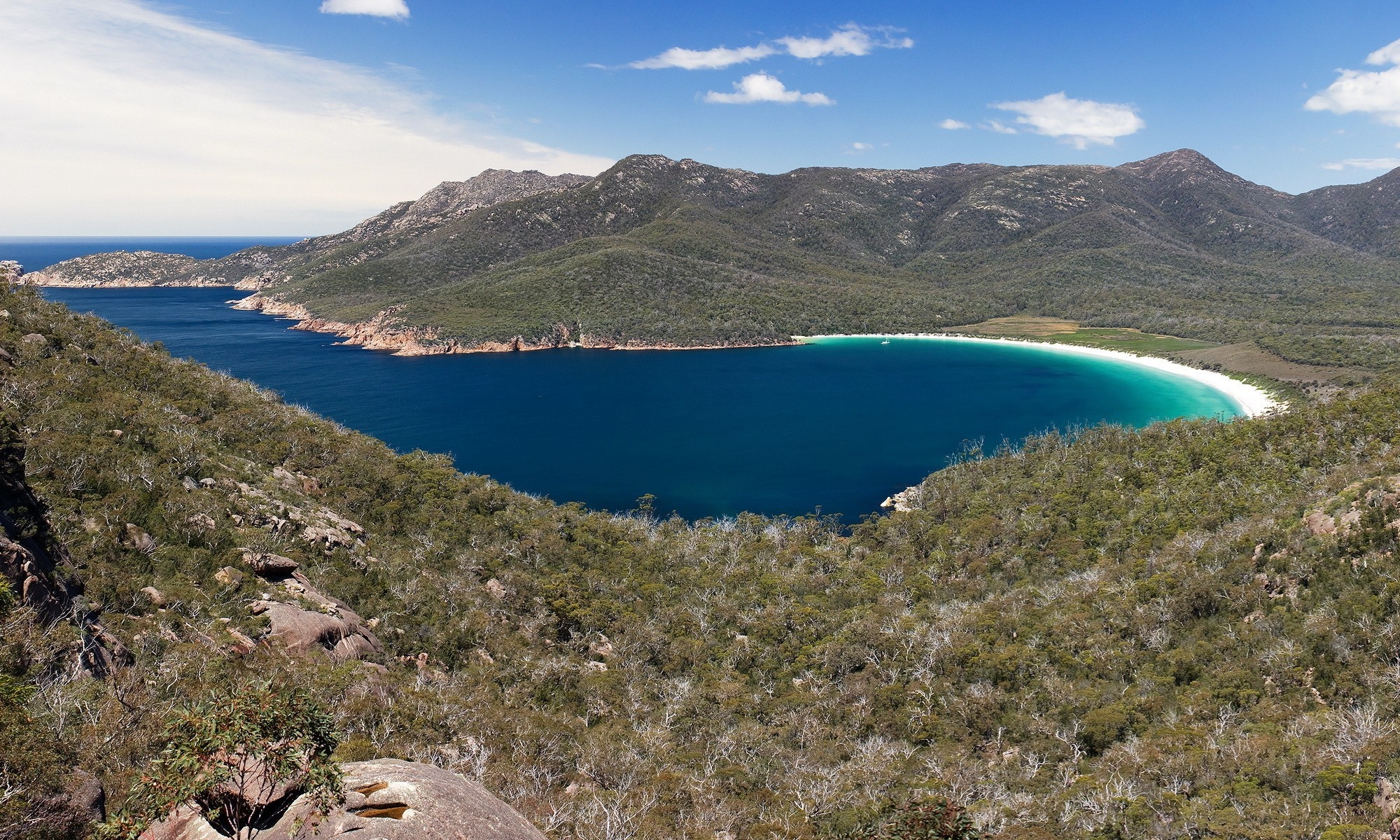Scenic bay with forested mountains and white sand beach HD Wallpaper