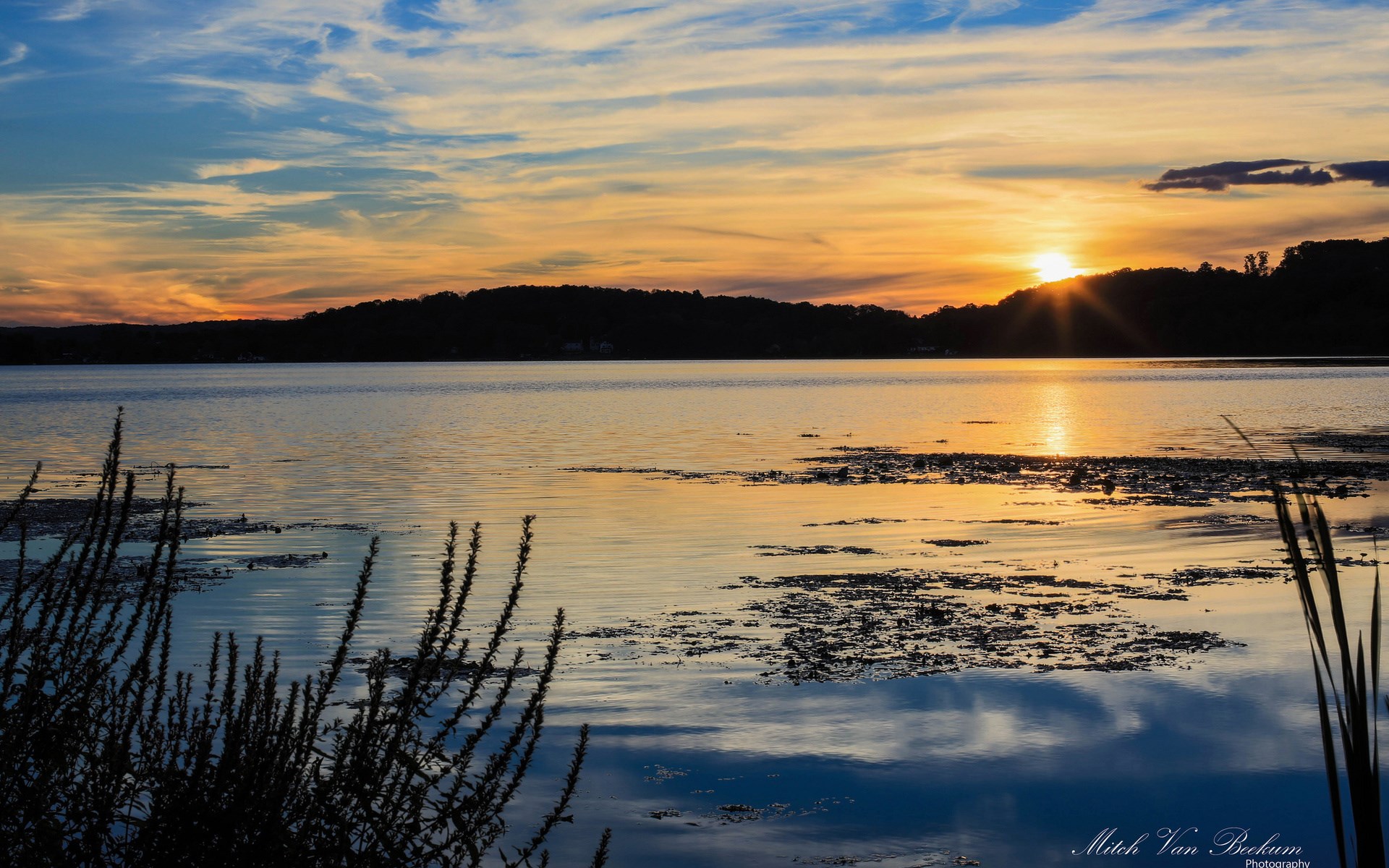 Sunset over a lake with silhouetted trees and clouds HD Wallpaper