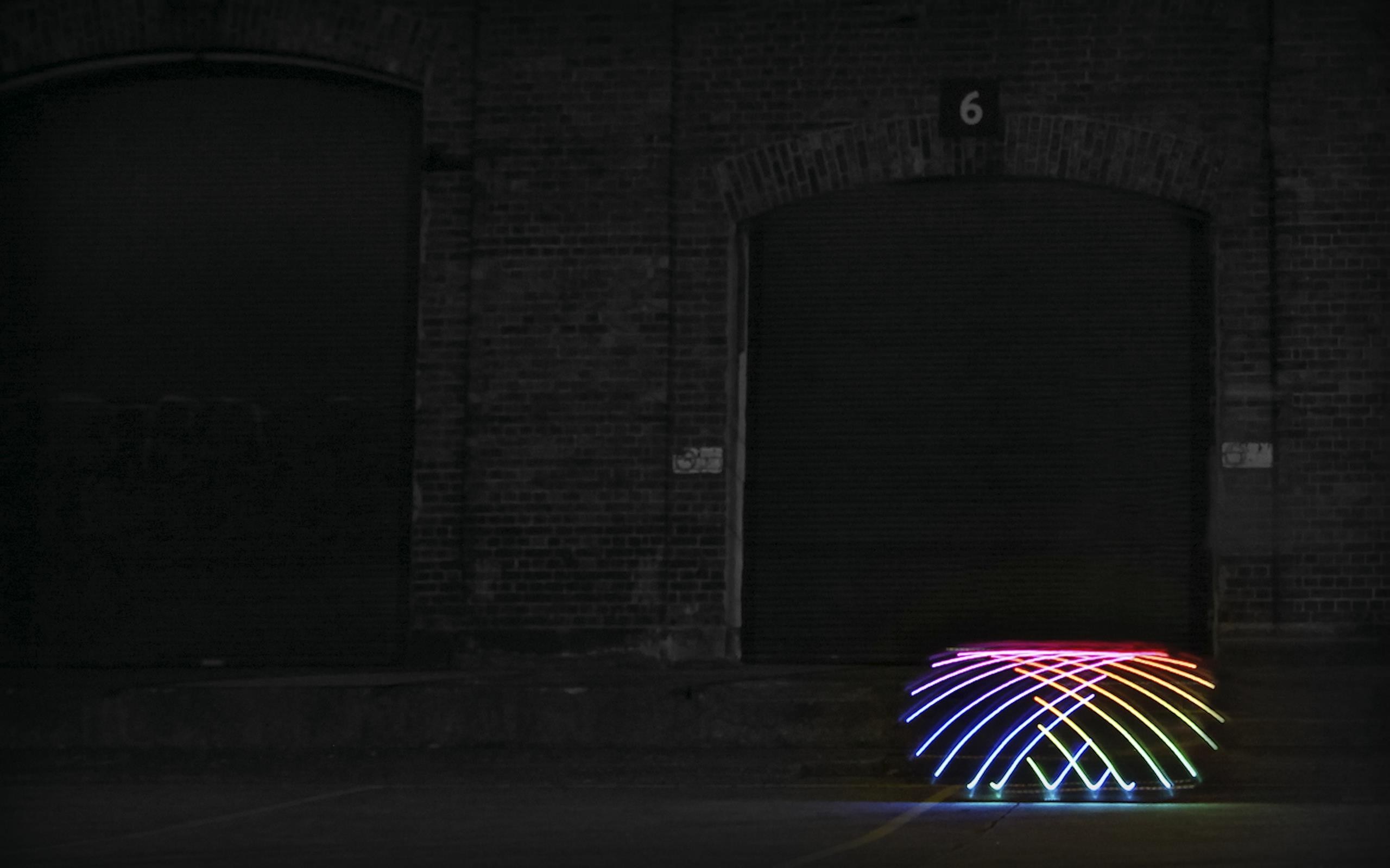 Light painting in front of brick buildings at night HD Wallpaper