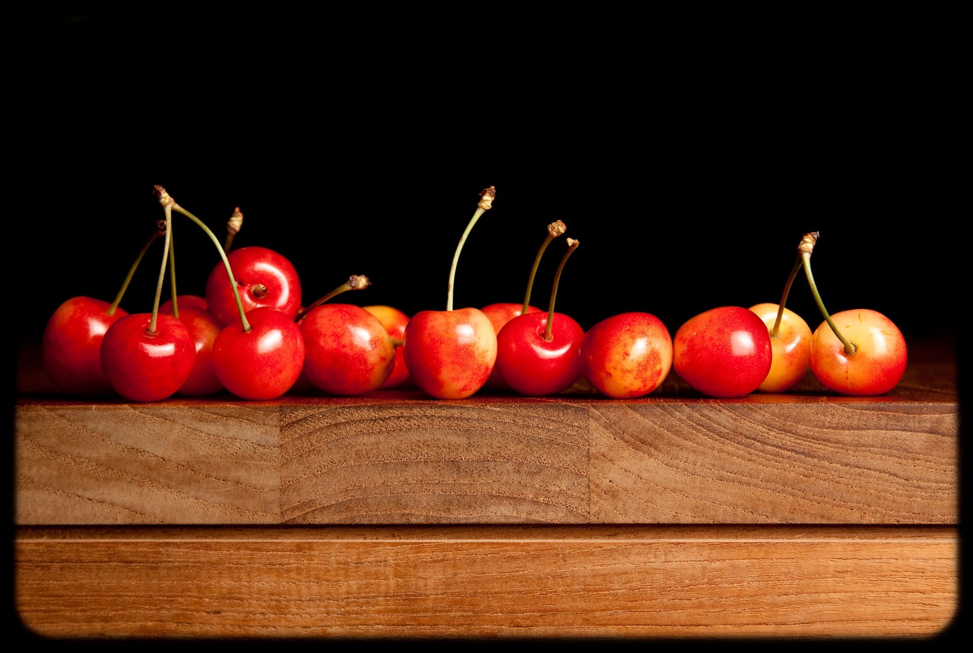 Cherries on a wooden surface with black background HD Wallpaper