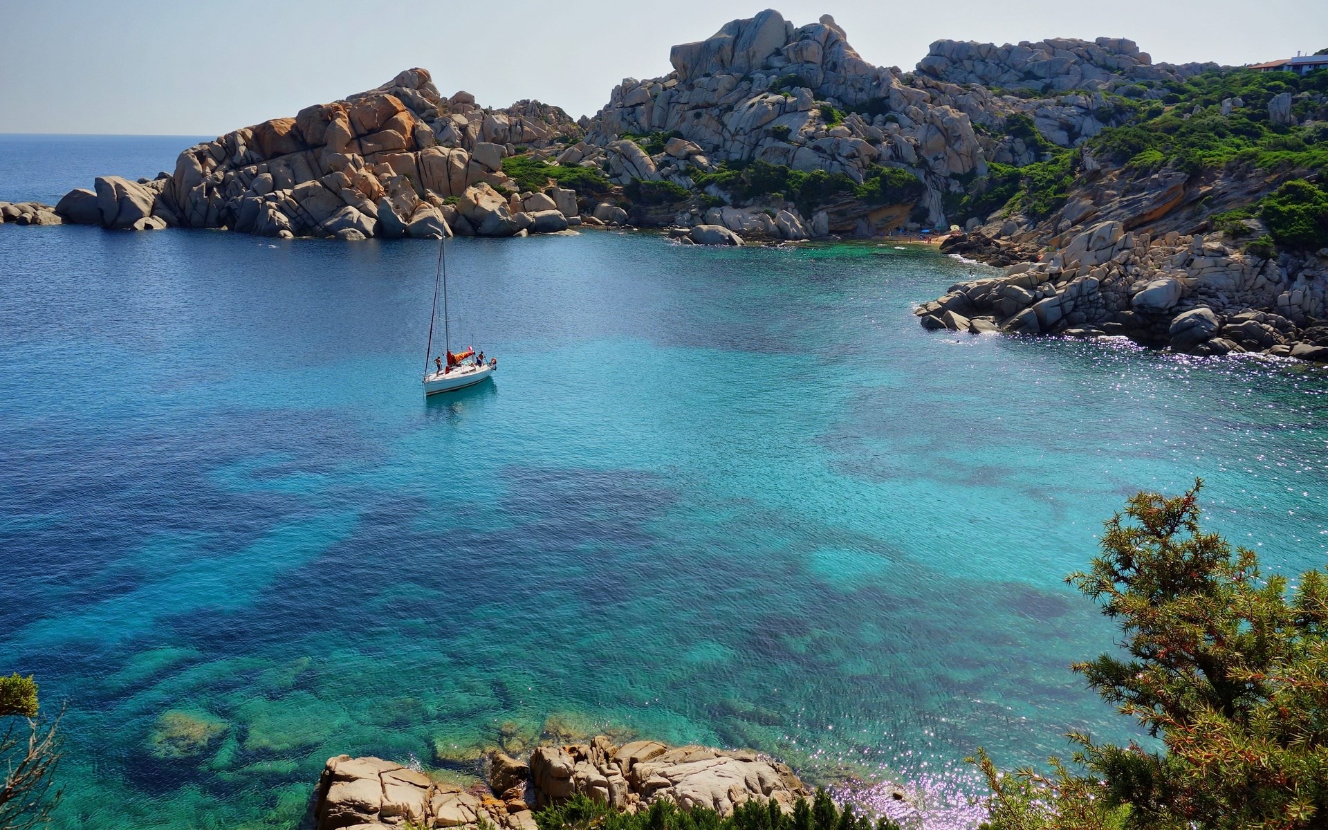 Sailboat in a turquoise bay with rocky coastline HD Wallpaper