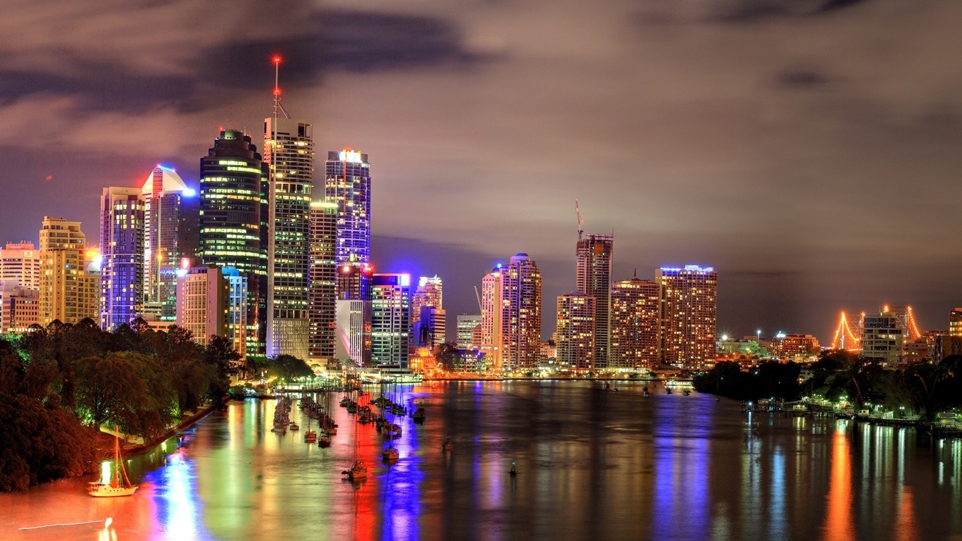 Cityscape skyline with illuminated skyscrapers at night over a river HD Wallpaper