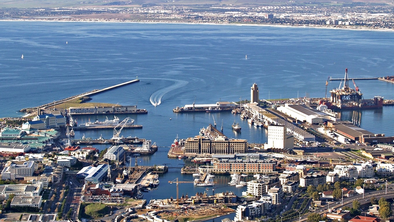 Aerial view of a busy port city with ships and buildings HD Wallpaper