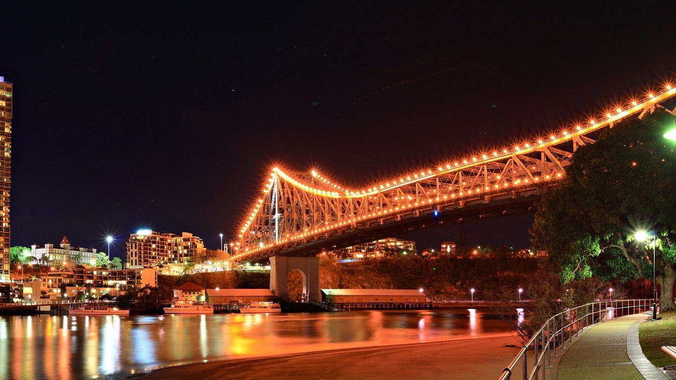 Cityscape at night with illuminated bridge and river HD Wallpaper