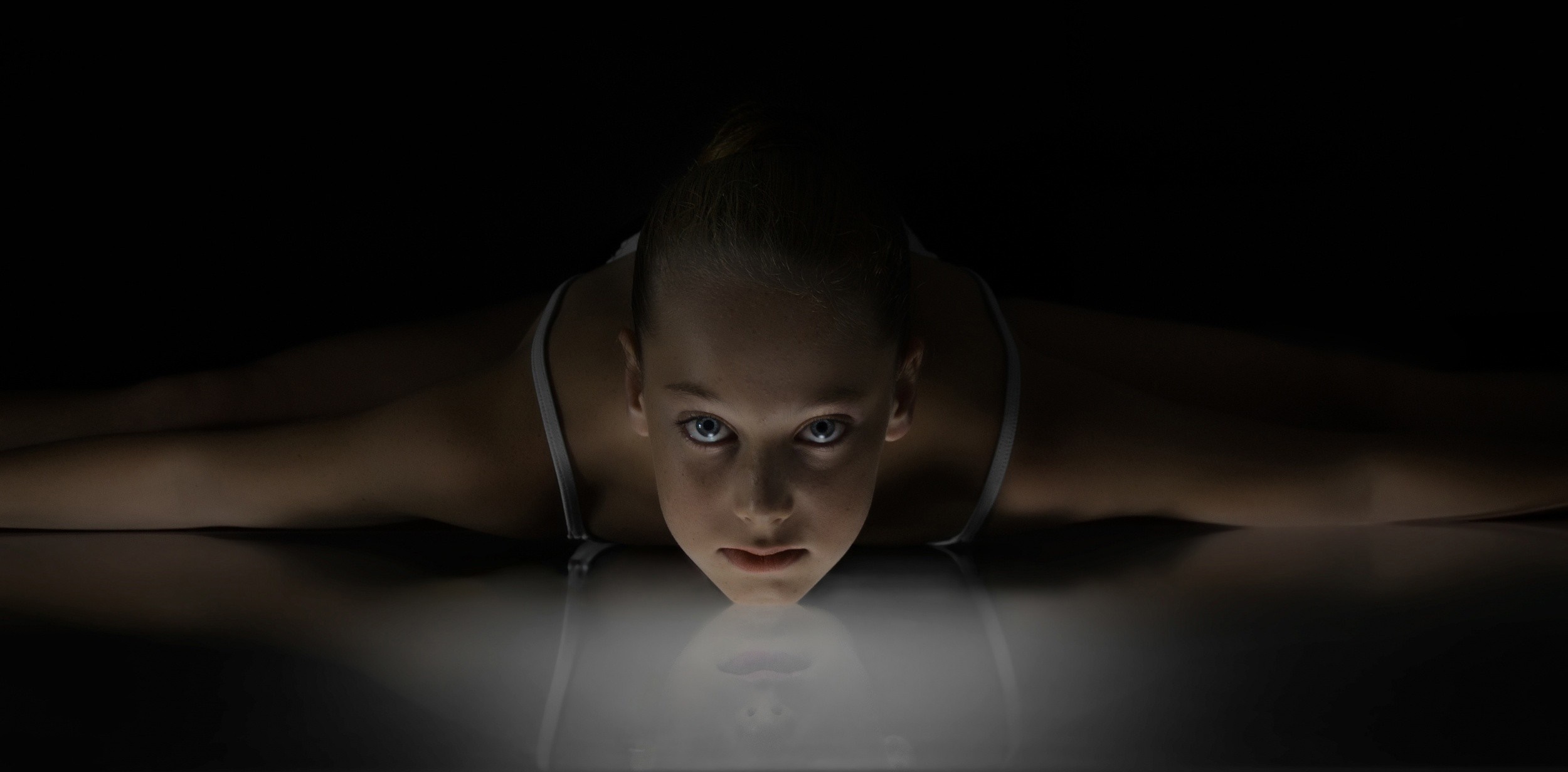Young gymnast in a split on a reflective surface HD Wallpaper