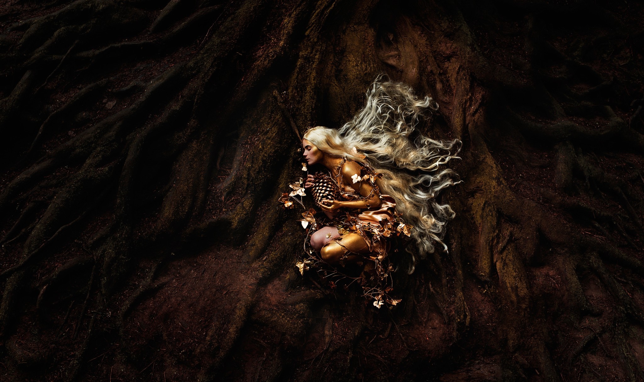 Golden woman with long blonde hair lying on tree roots HD Wallpaper
