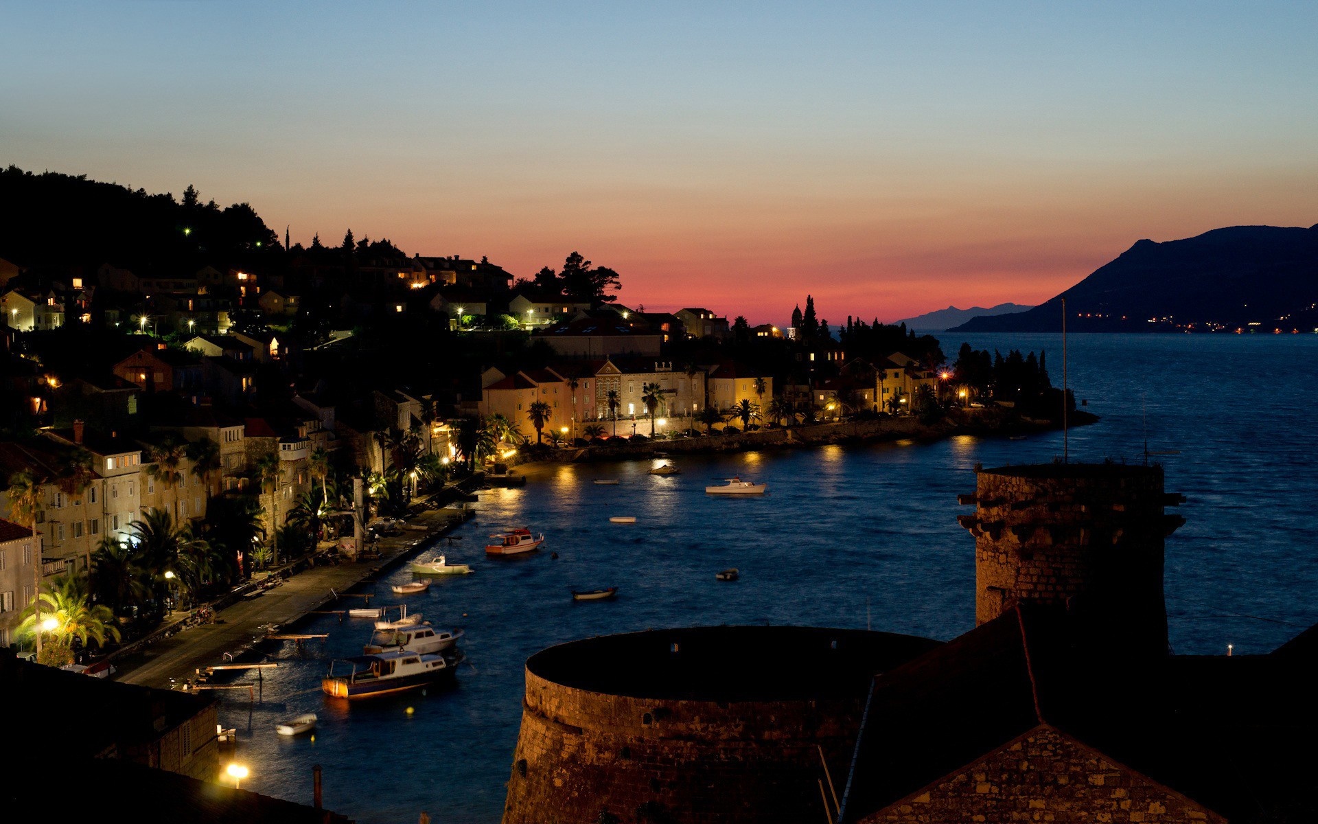Coastal town at dusk with boats in the bay HD Wallpaper