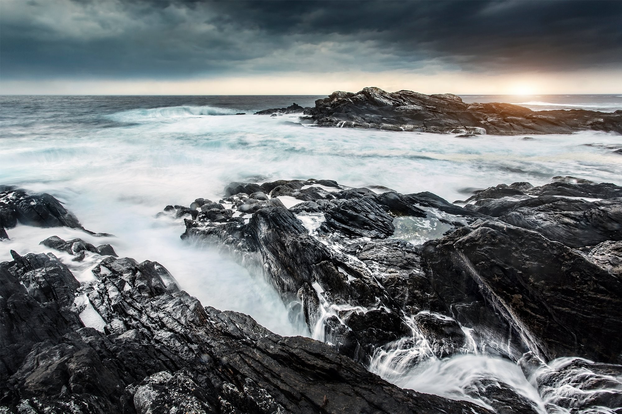 Waves crashing on rocky shore with stormy clouds HD Wallpaper
