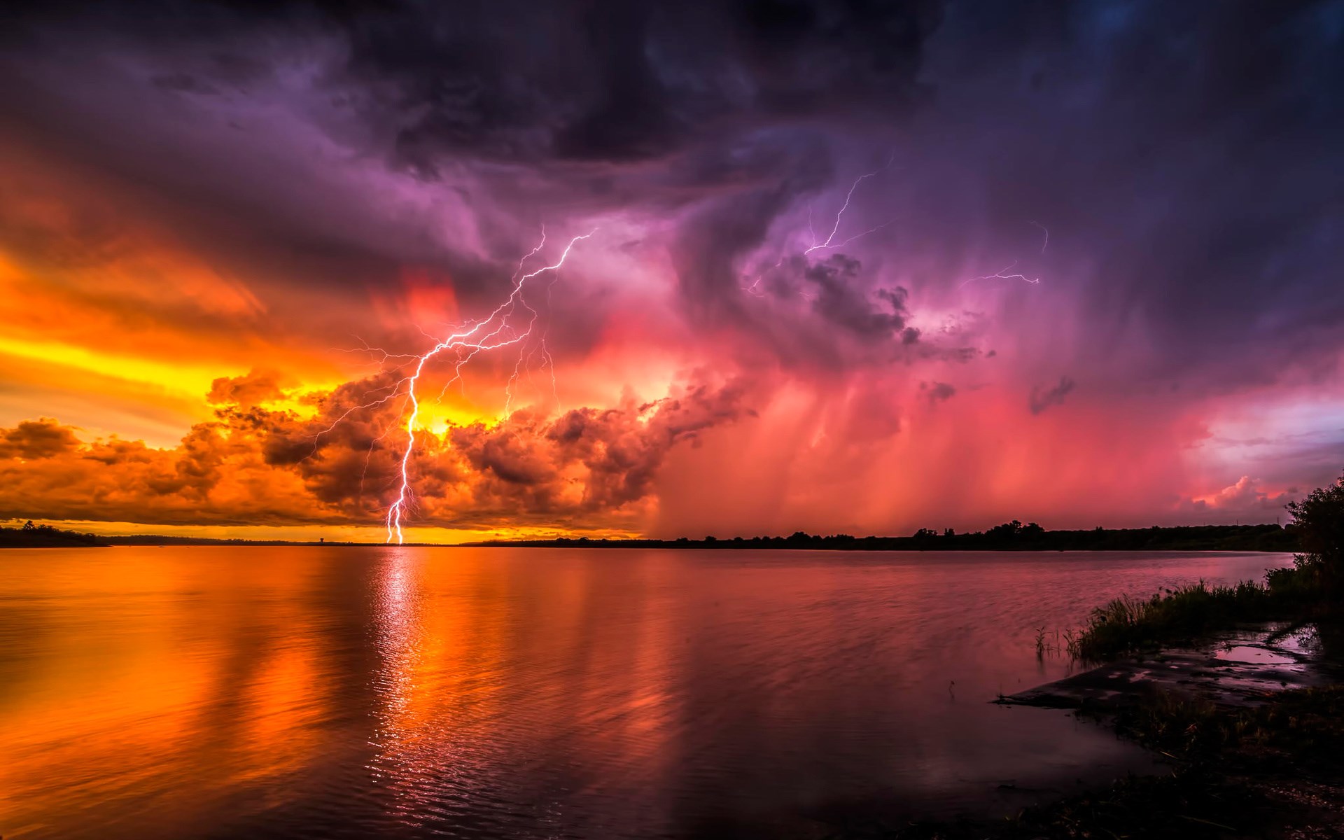 Lightning strikes over a lake during a colorful storm HD Wallpaper