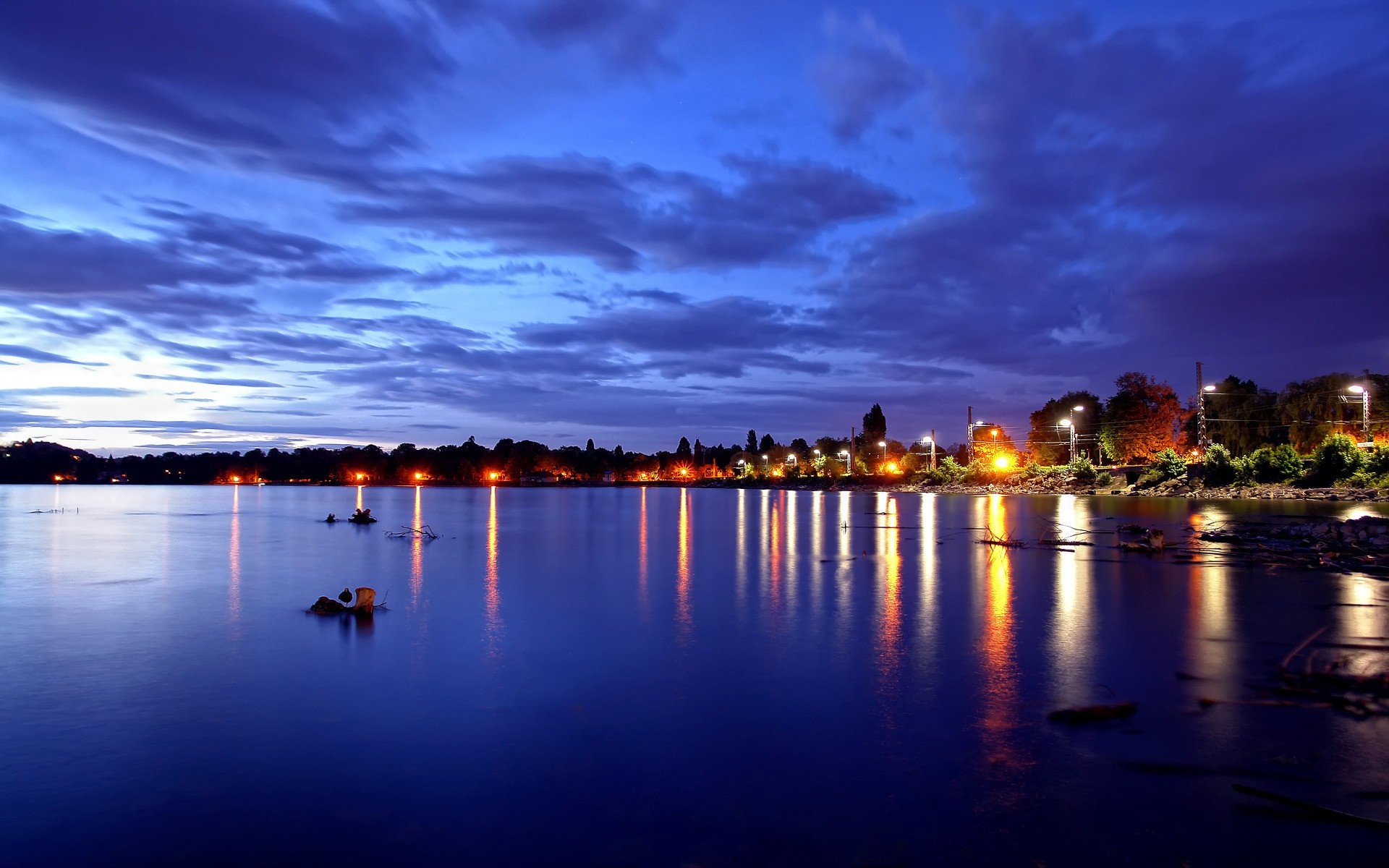 City lights reflecting on a lake at dusk HD Wallpaper
