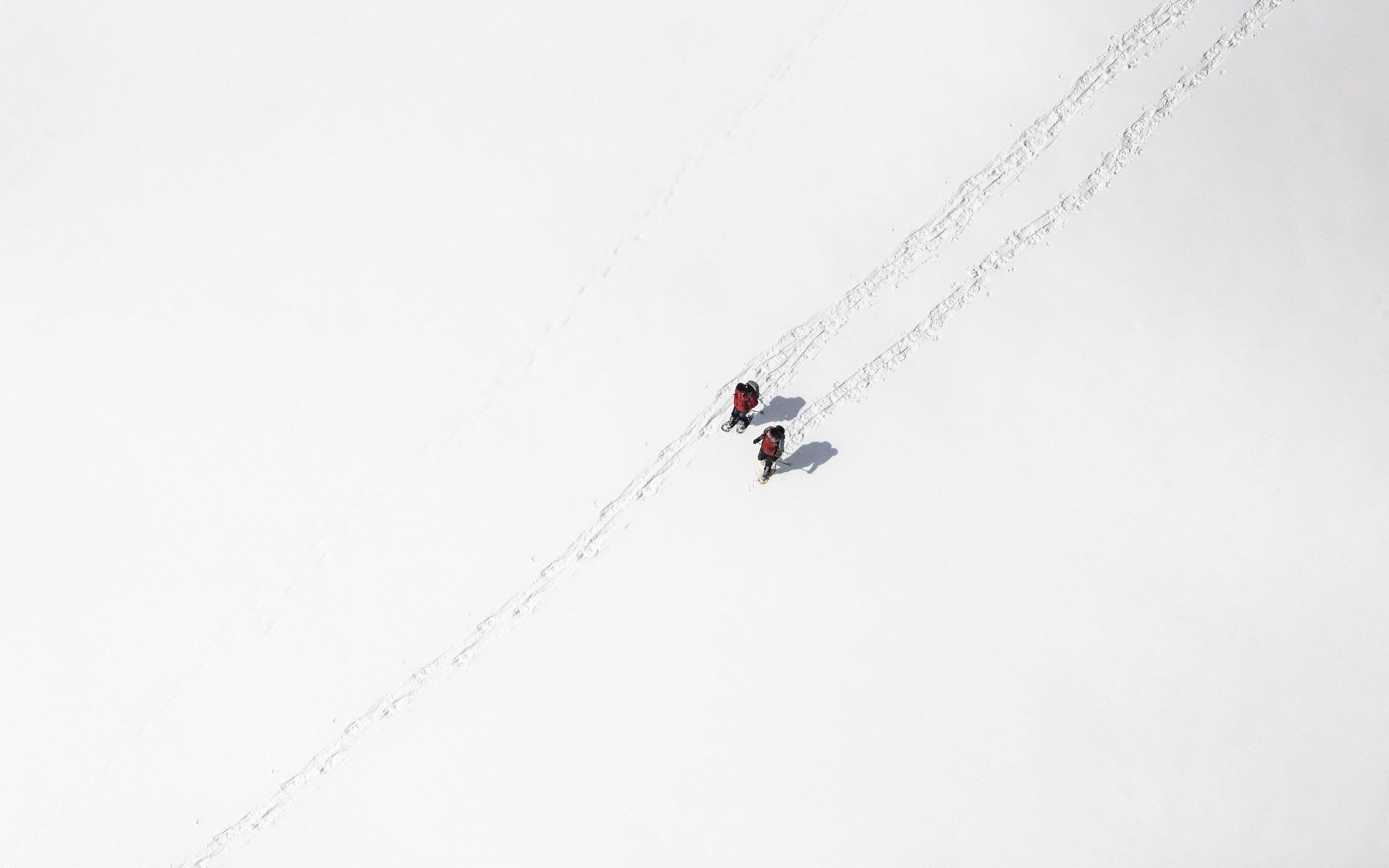 Two skiers in red jackets on a snowy slope HD Wallpaper