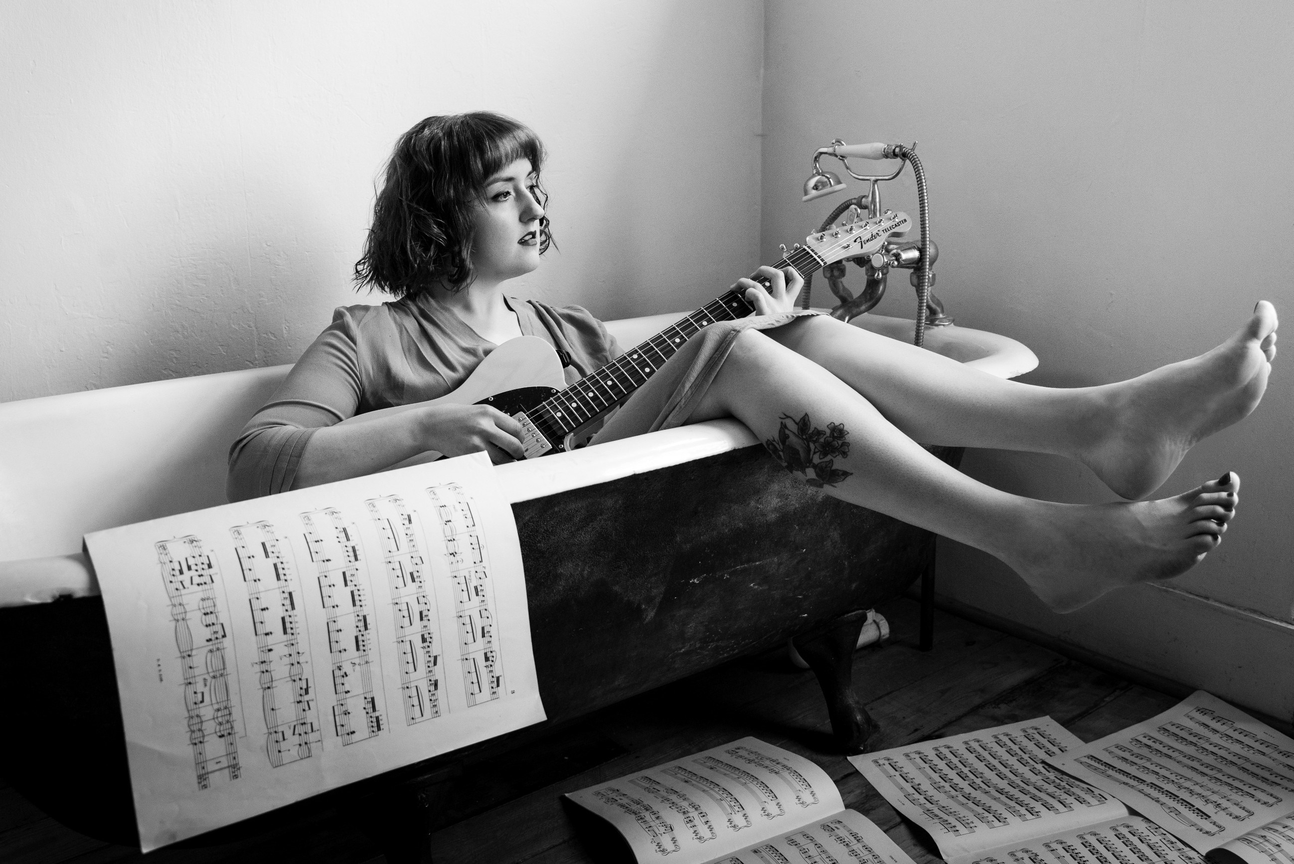Woman playing guitar in a bathtub with sheet music HD Wallpaper