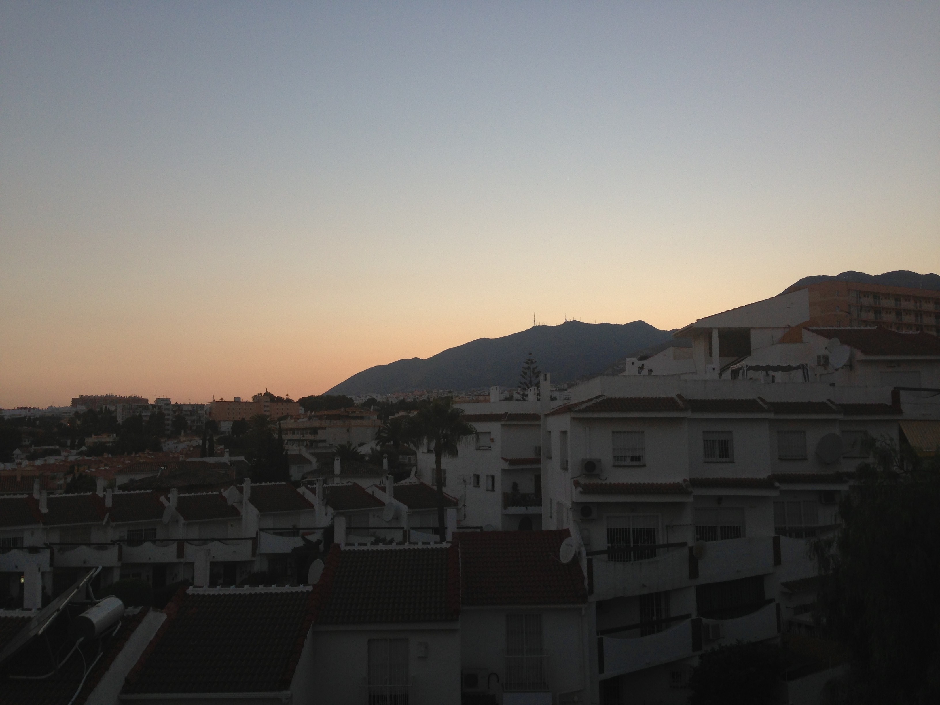 Cityscape at sunset with mountains in the background HD Wallpaper