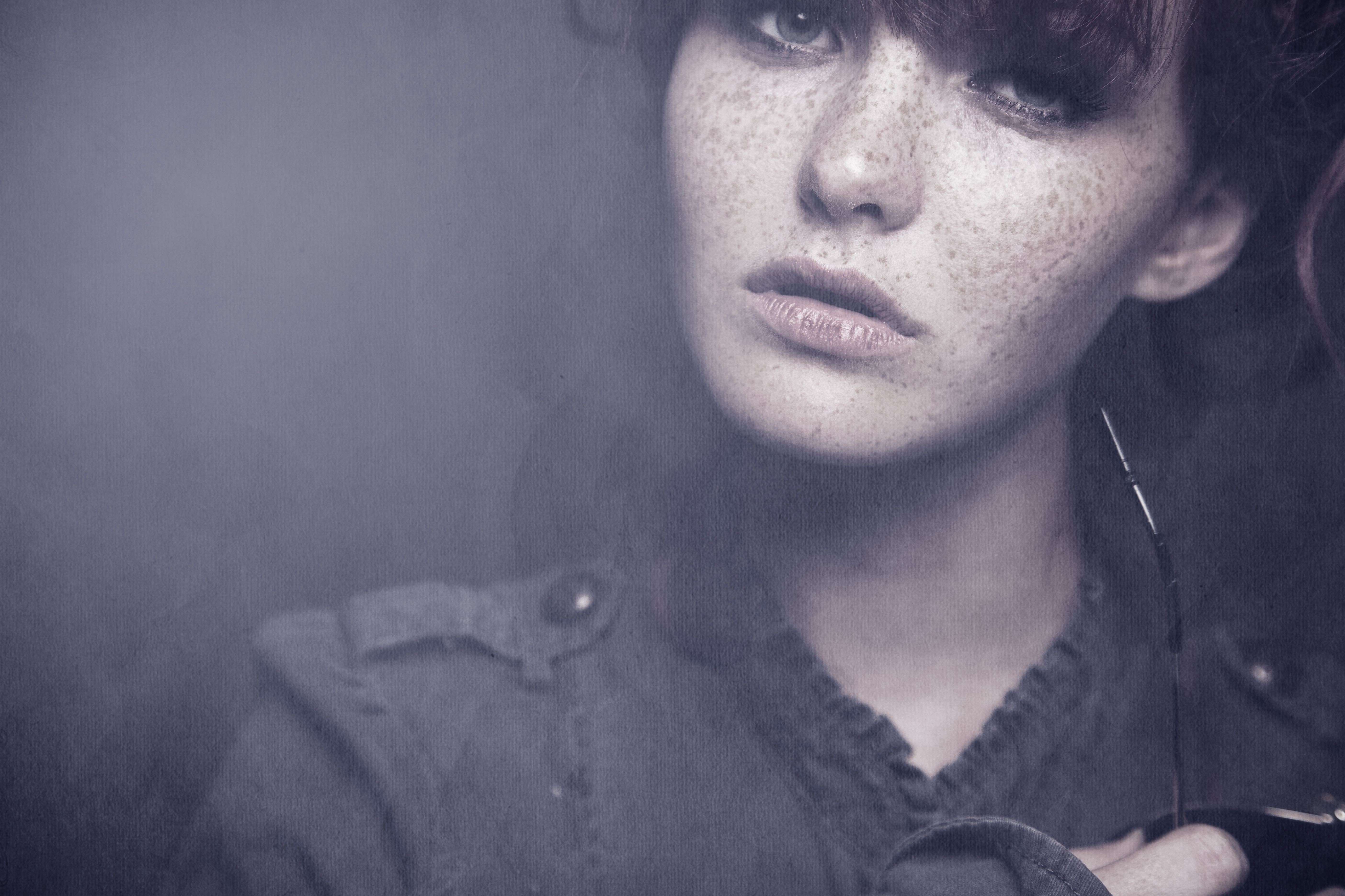 Woman with freckles in a dark, moody portrait HD Wallpaper