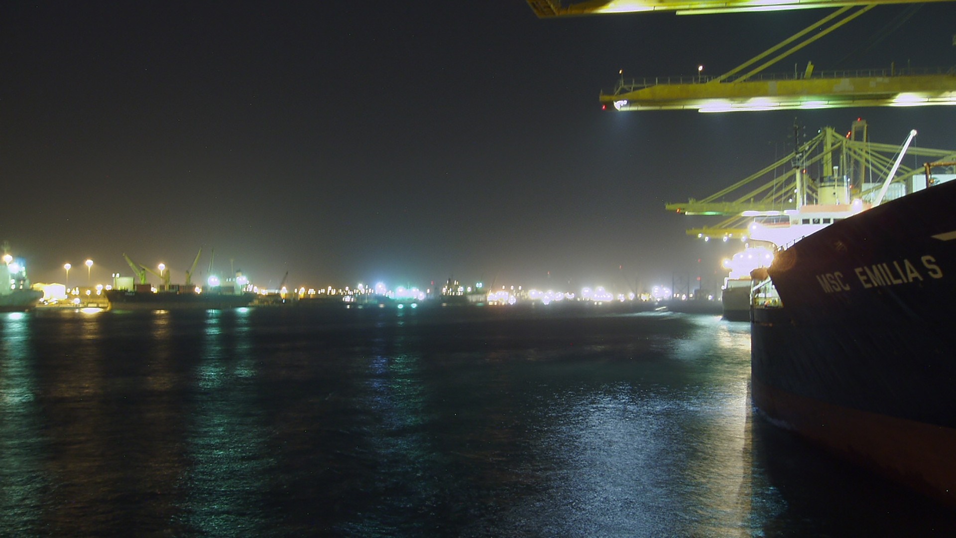 Night view of a busy port with ships and cranes HD Wallpaper