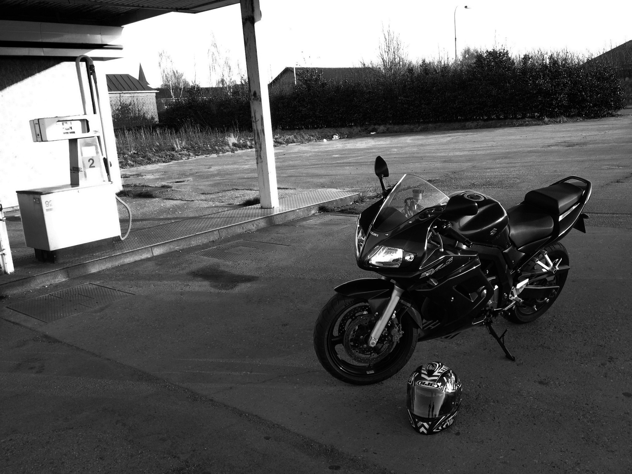 Black Suzuki SV 650 motorcycle and helmet at gas station HD Wallpaper