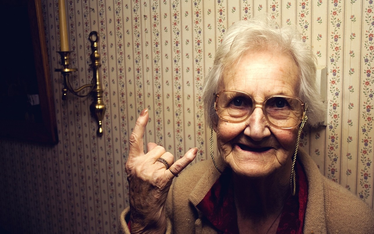 Elderly woman with glasses making rock on gesture HD Wallpaper
