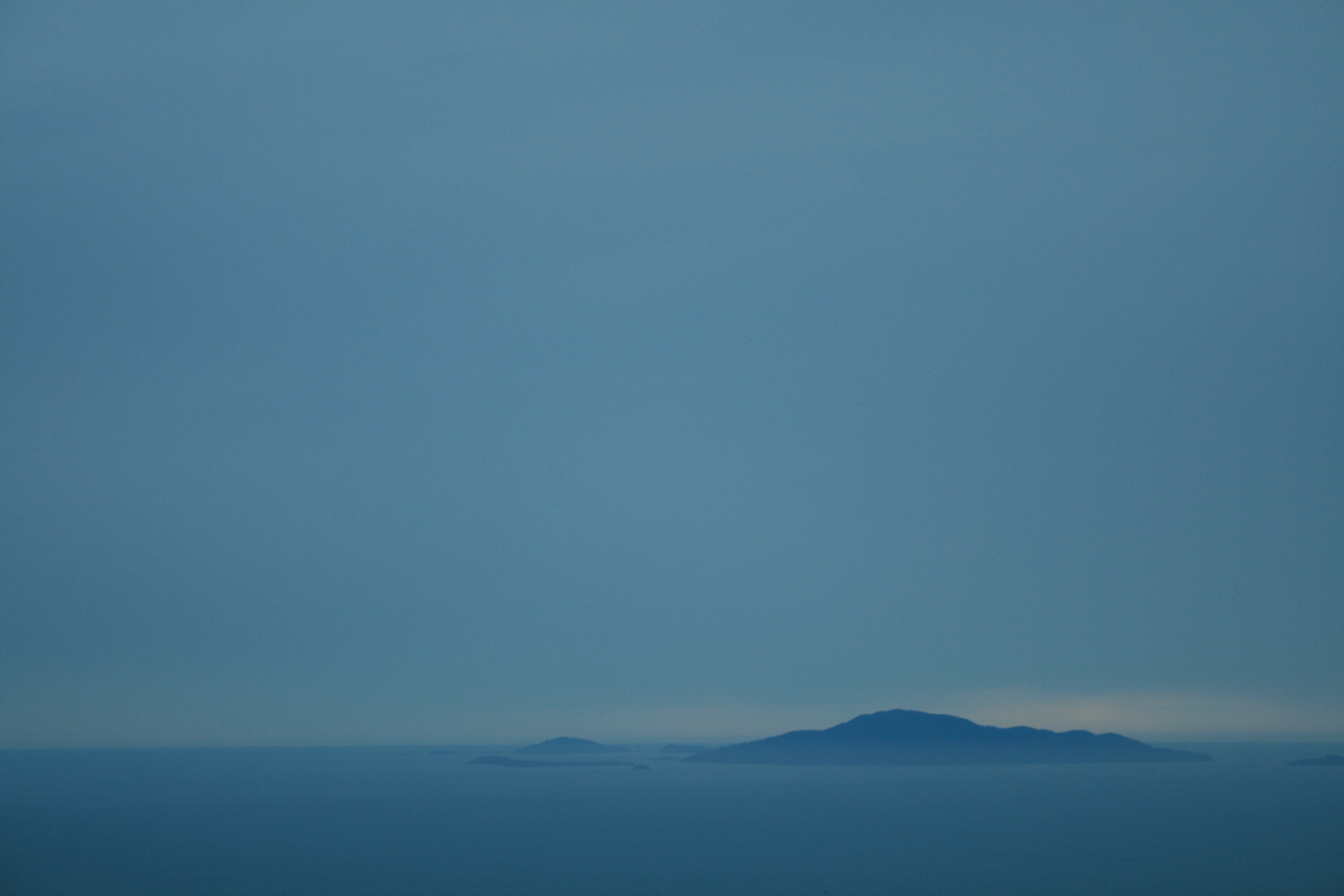 Islands on the horizon at dusk over the sea HD Wallpaper