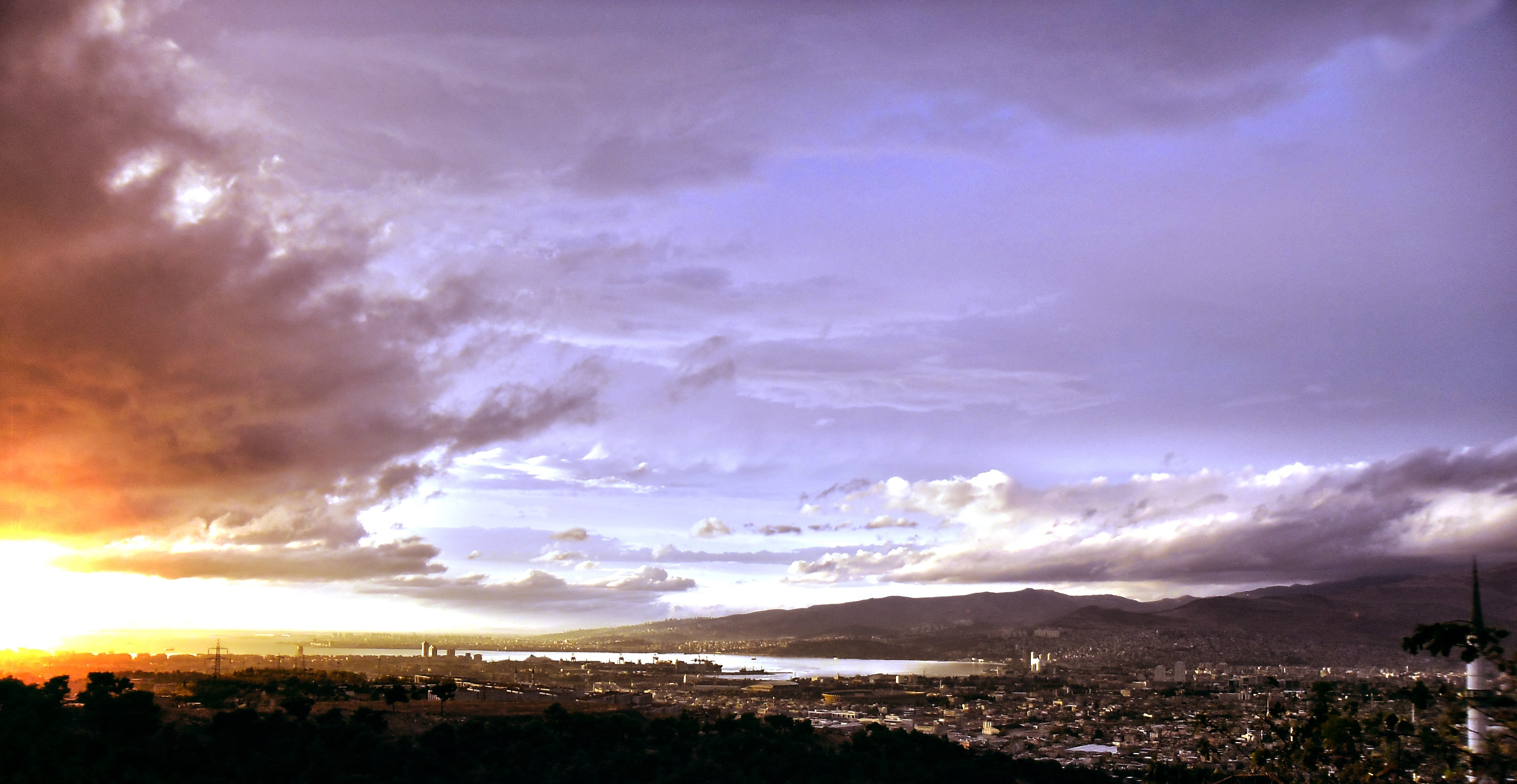Sunset over a coastal city with dramatic clouds HD Wallpaper
