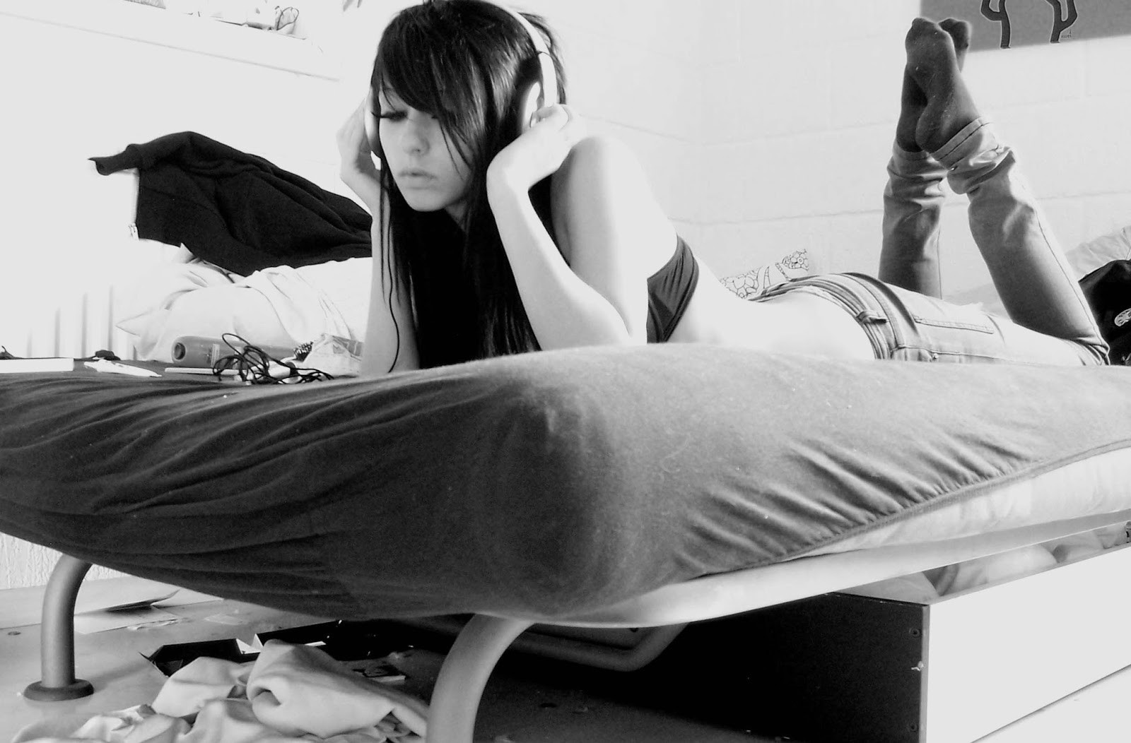 Young woman with headphones lying on a bed HD Wallpaper