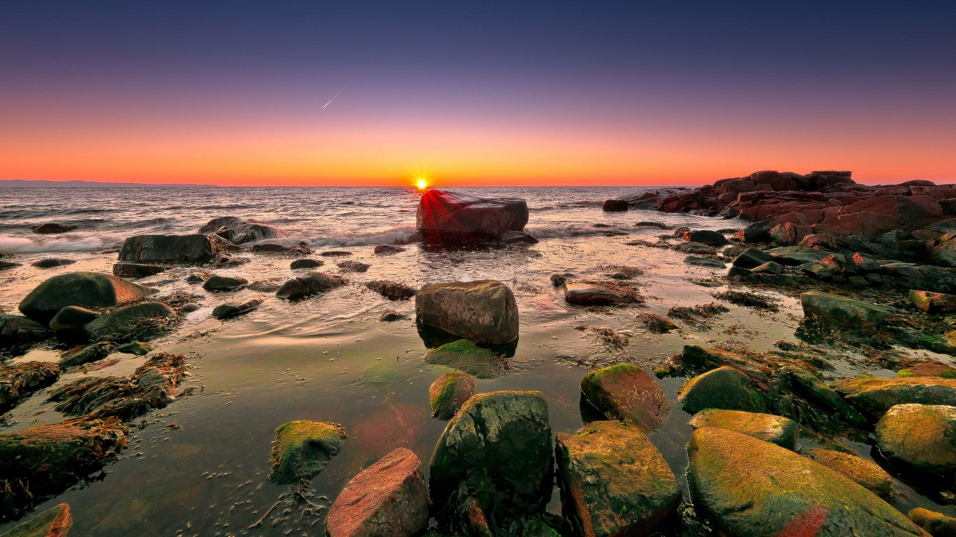Sunset over a rocky coastline with waves HD Wallpaper