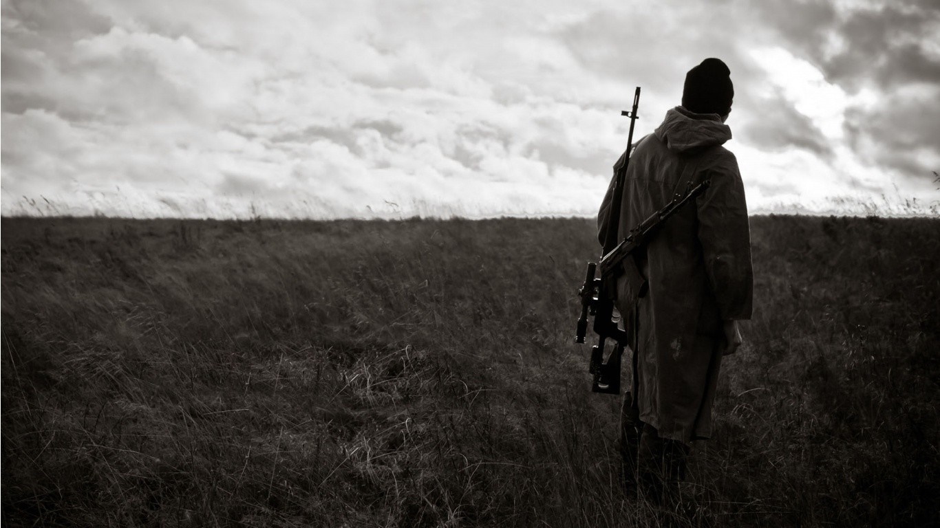 Soldier with sniper rifle in a field under cloudy sky HD Wallpaper