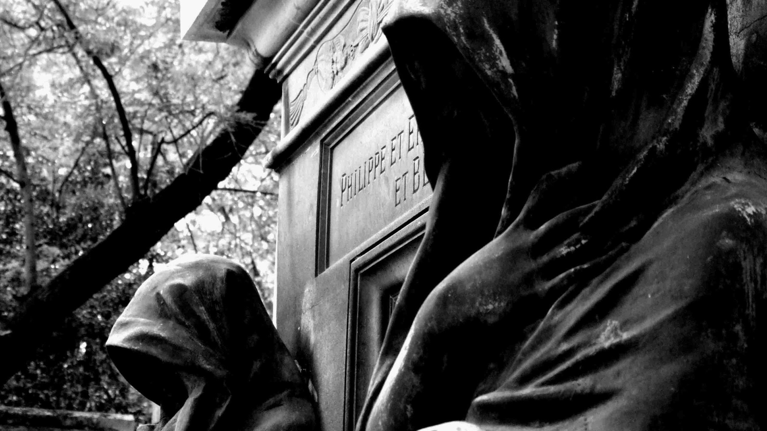 Monochrome statue of cloaked figures in a cemetery HD Wallpaper