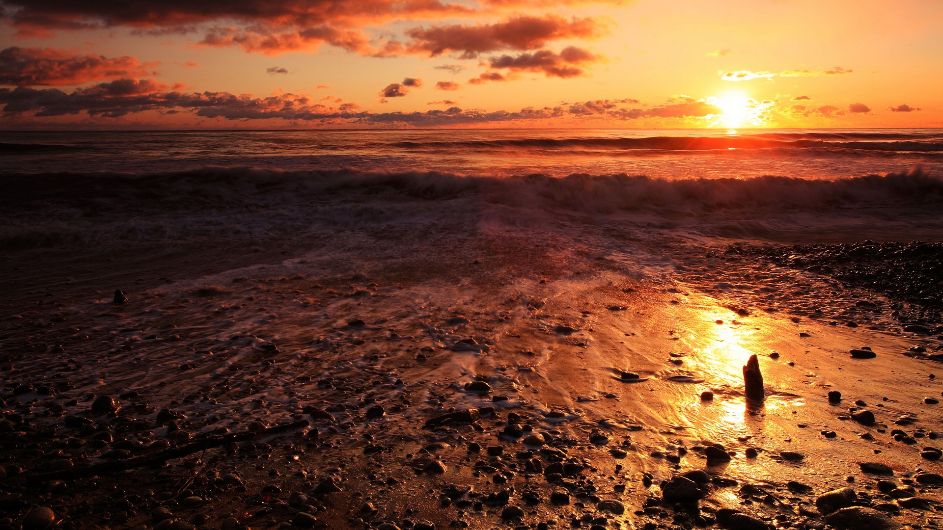 Sunset over a rocky beach with waves HD Wallpaper