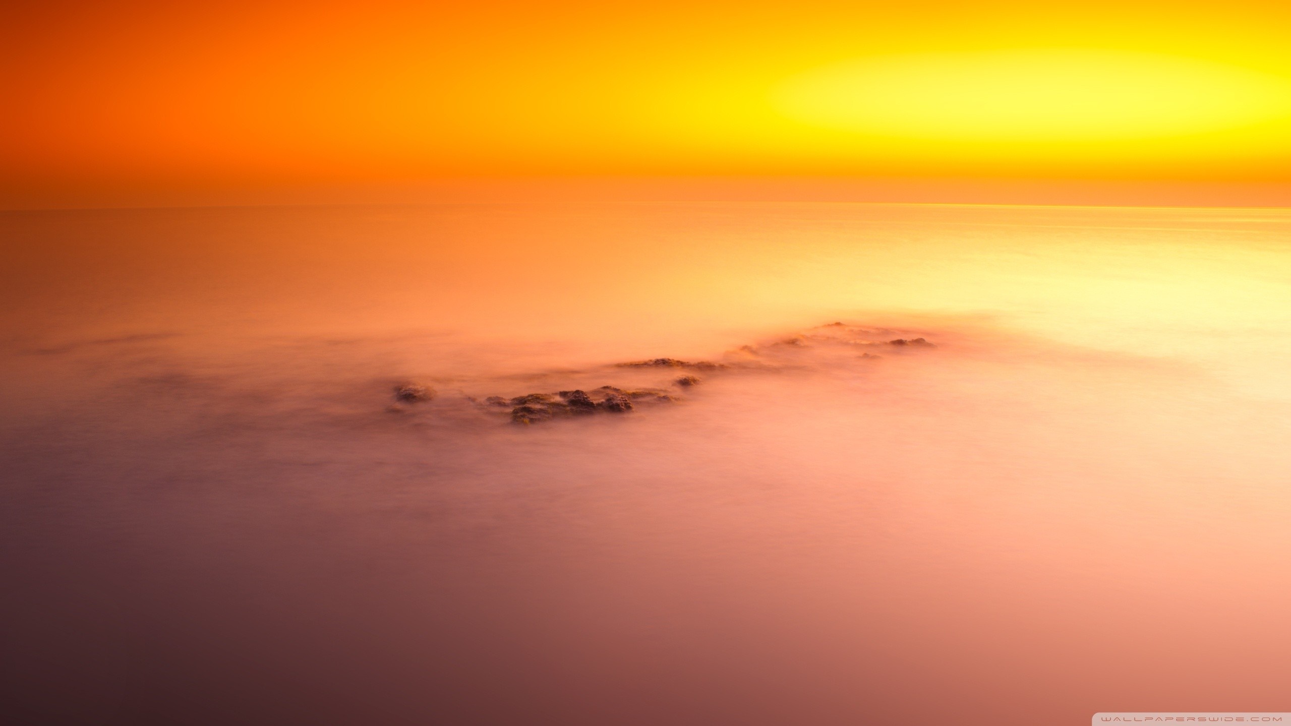 Sunset over the ocean with fog and rocks HD Wallpaper