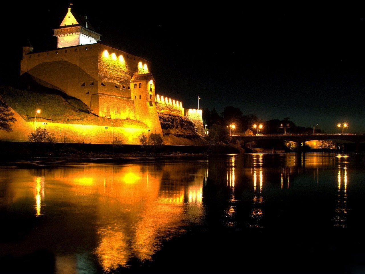 Illuminated castle at night reflected in water HD Wallpaper