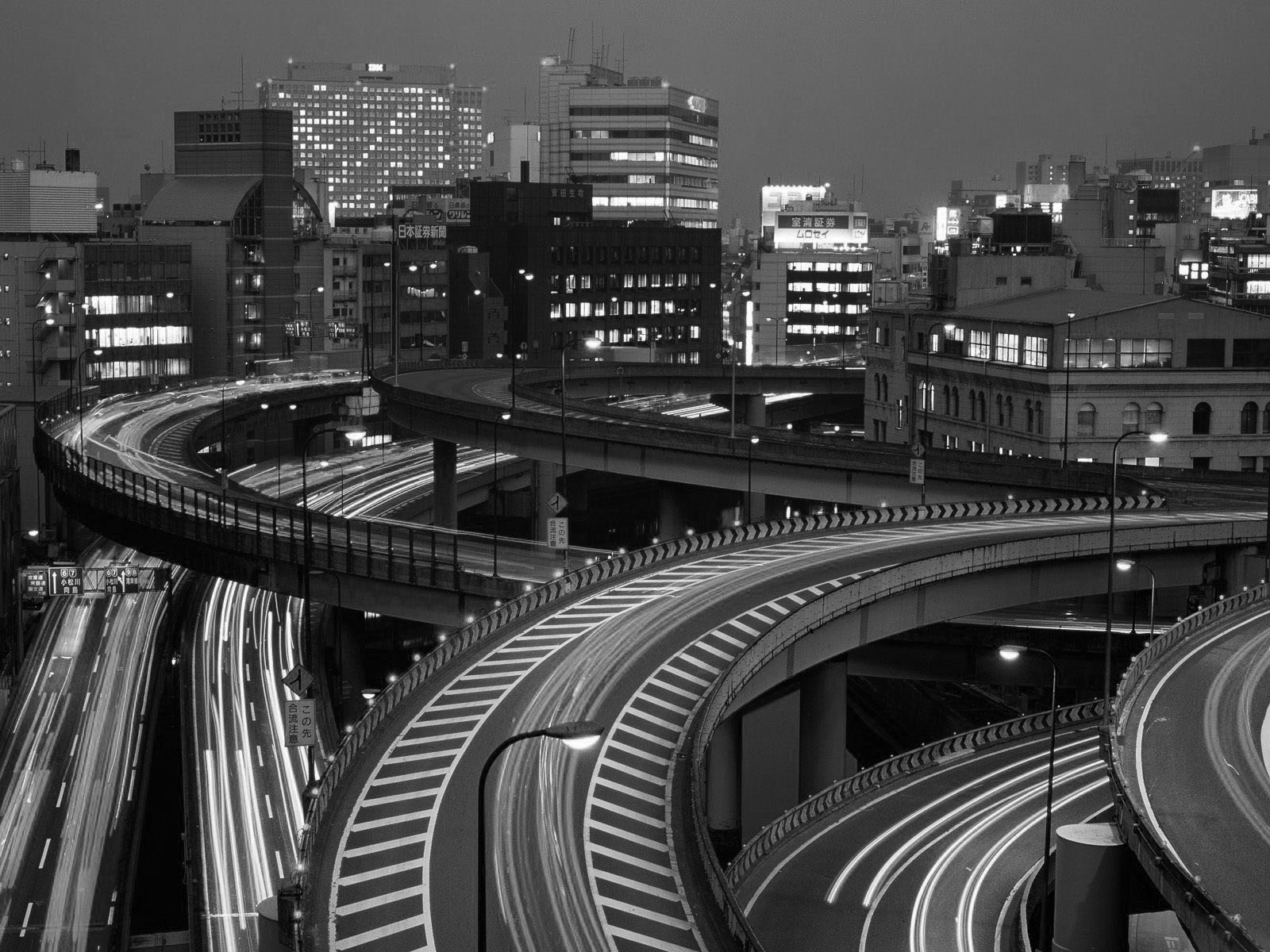 Monochrome cityscape with light trails on a highway overpass at night HD Wallpaper
