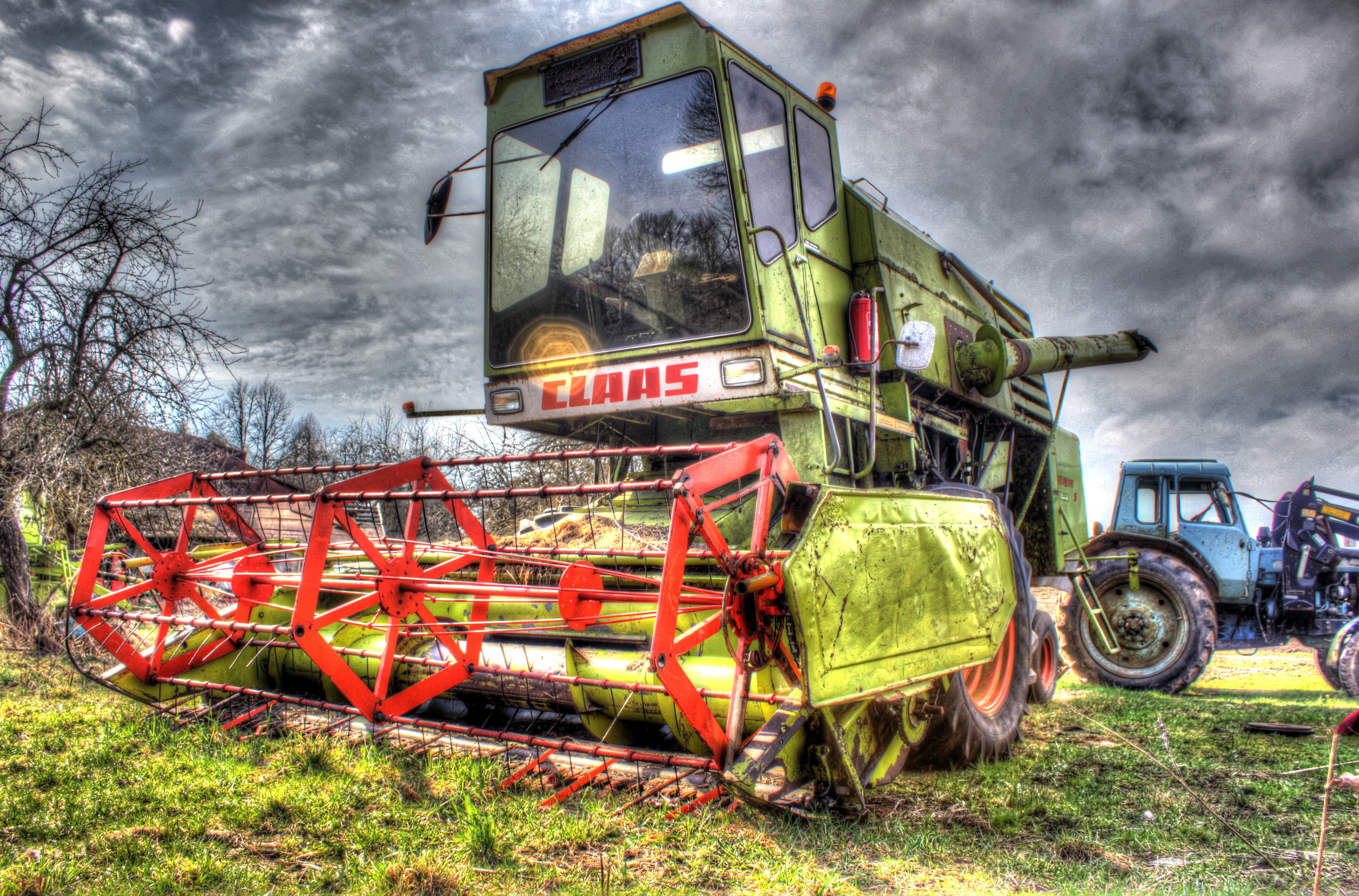 Green Claas combine harvester and blue tractor in a field HD Wallpaper