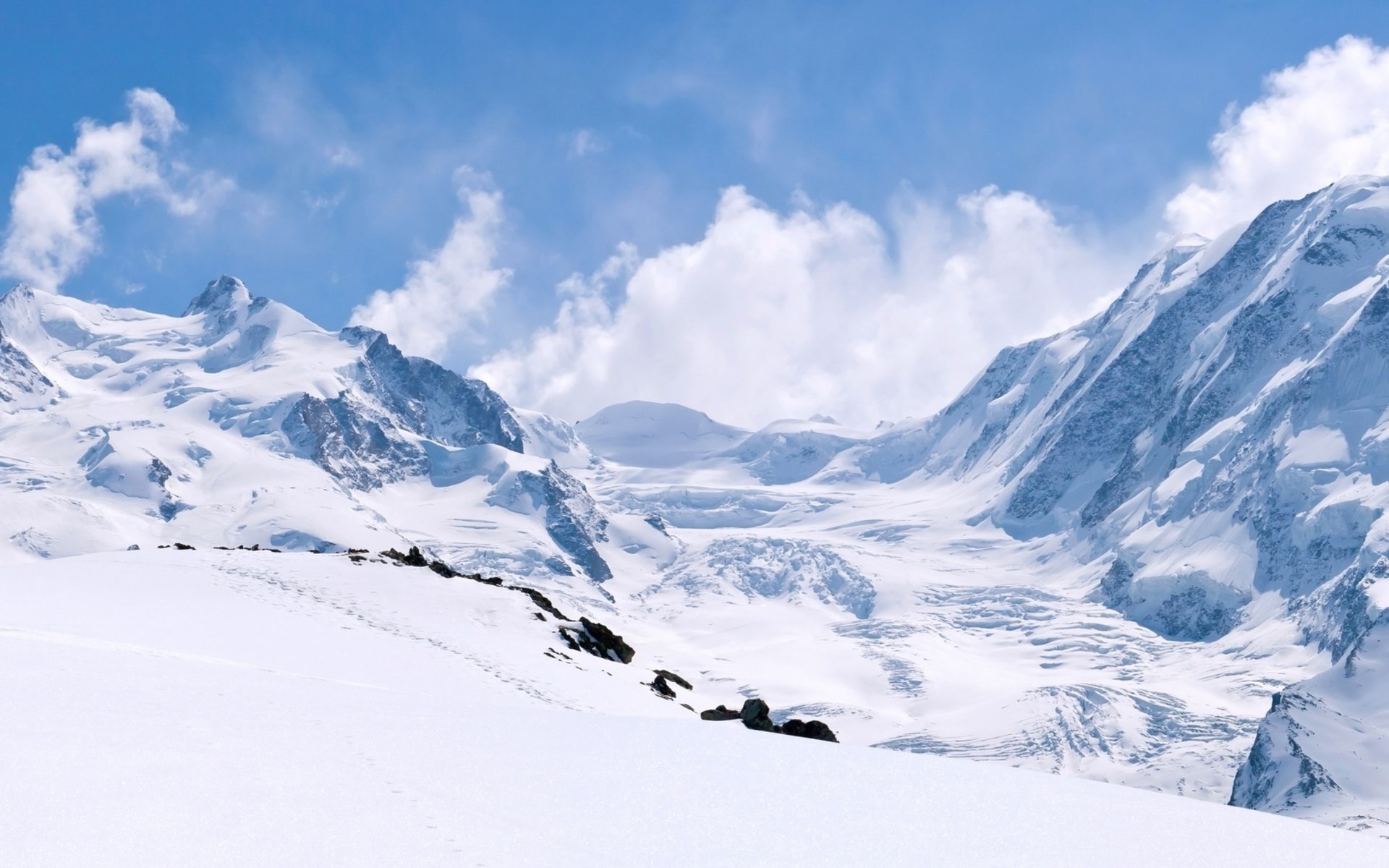 Snowy mountain range under a blue sky with clouds HD Wallpaper