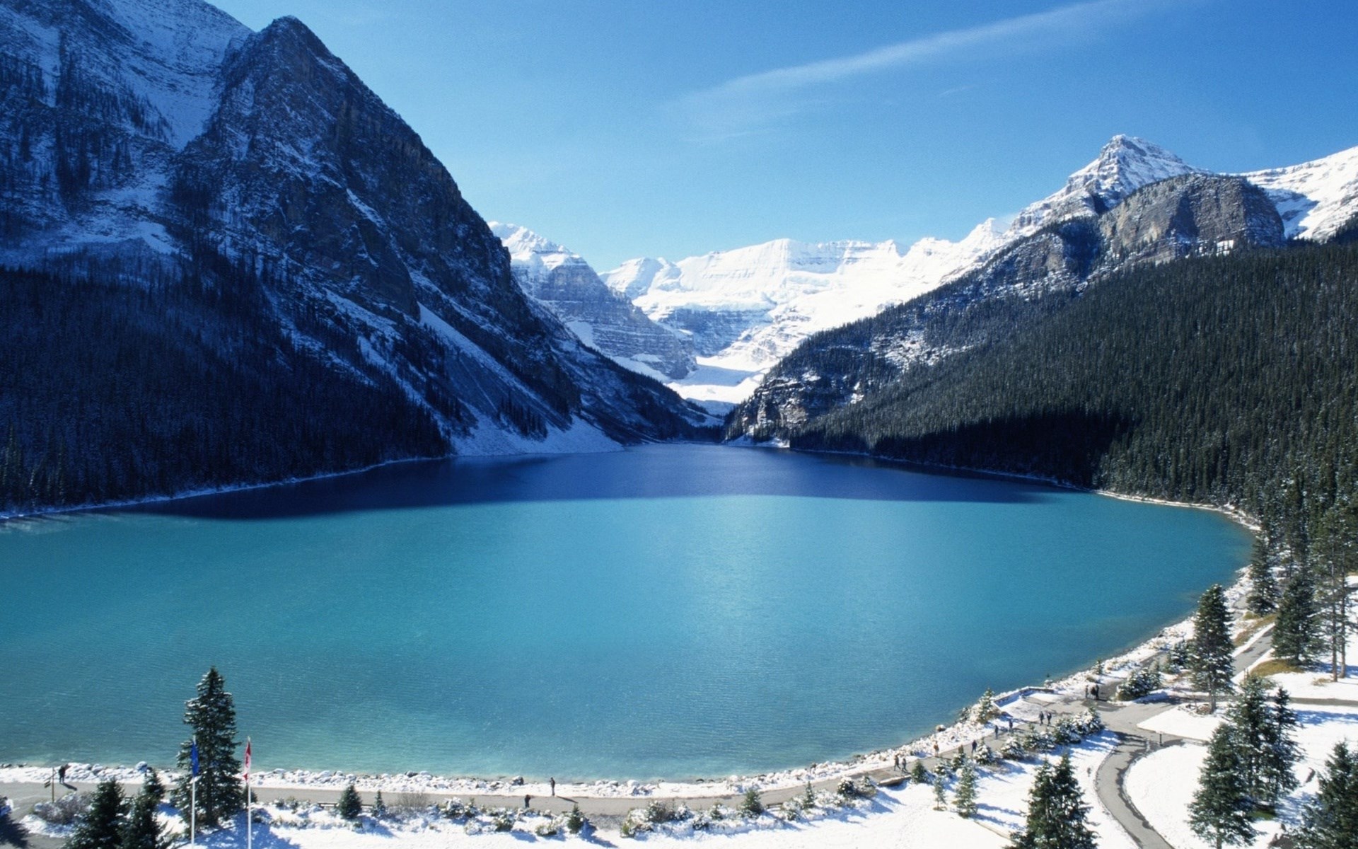 Turquoise lake surrounded by snow-capped mountains and pine trees HD Wallpaper