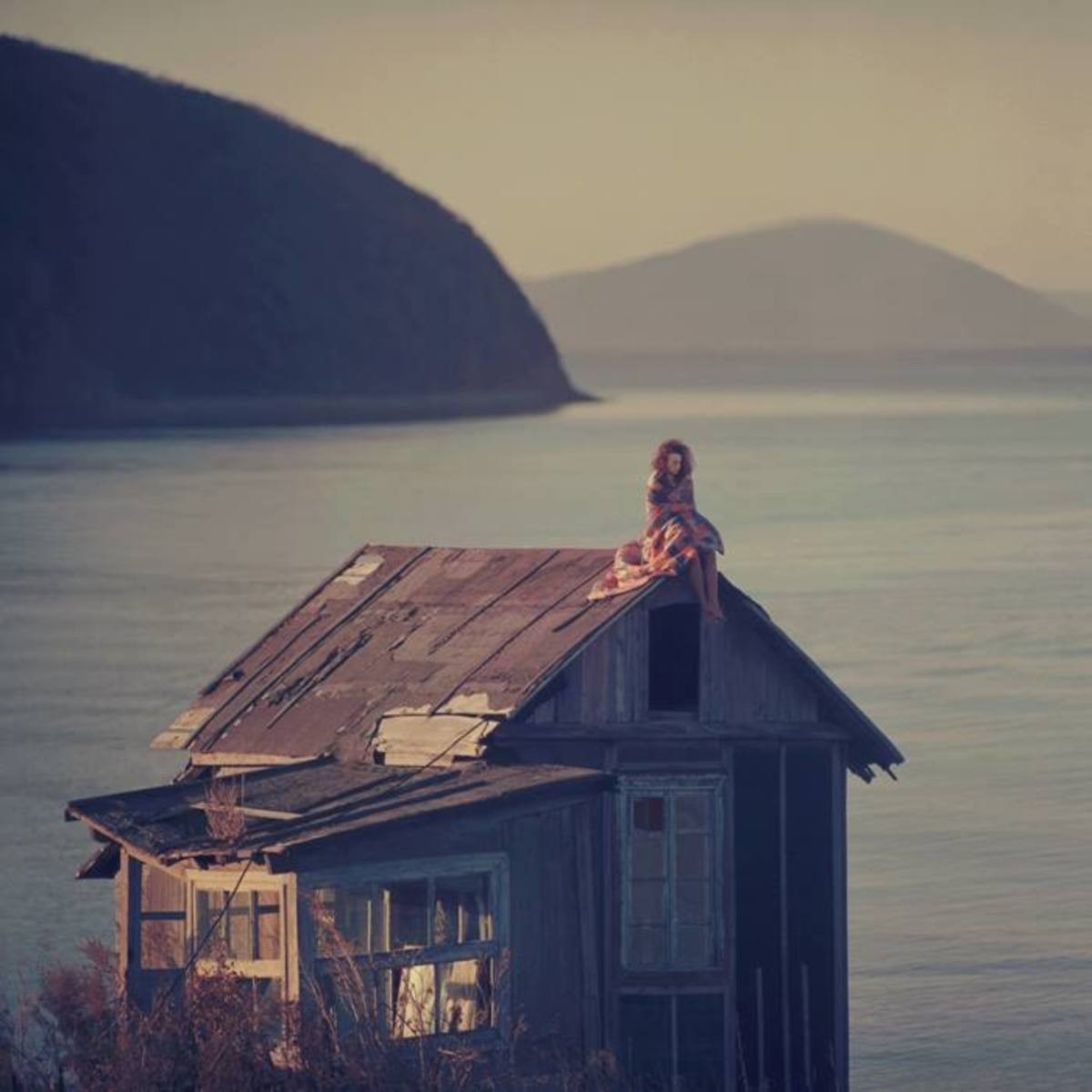 Woman sitting on the roof of a dilapidated house by the sea HD Wallpaper