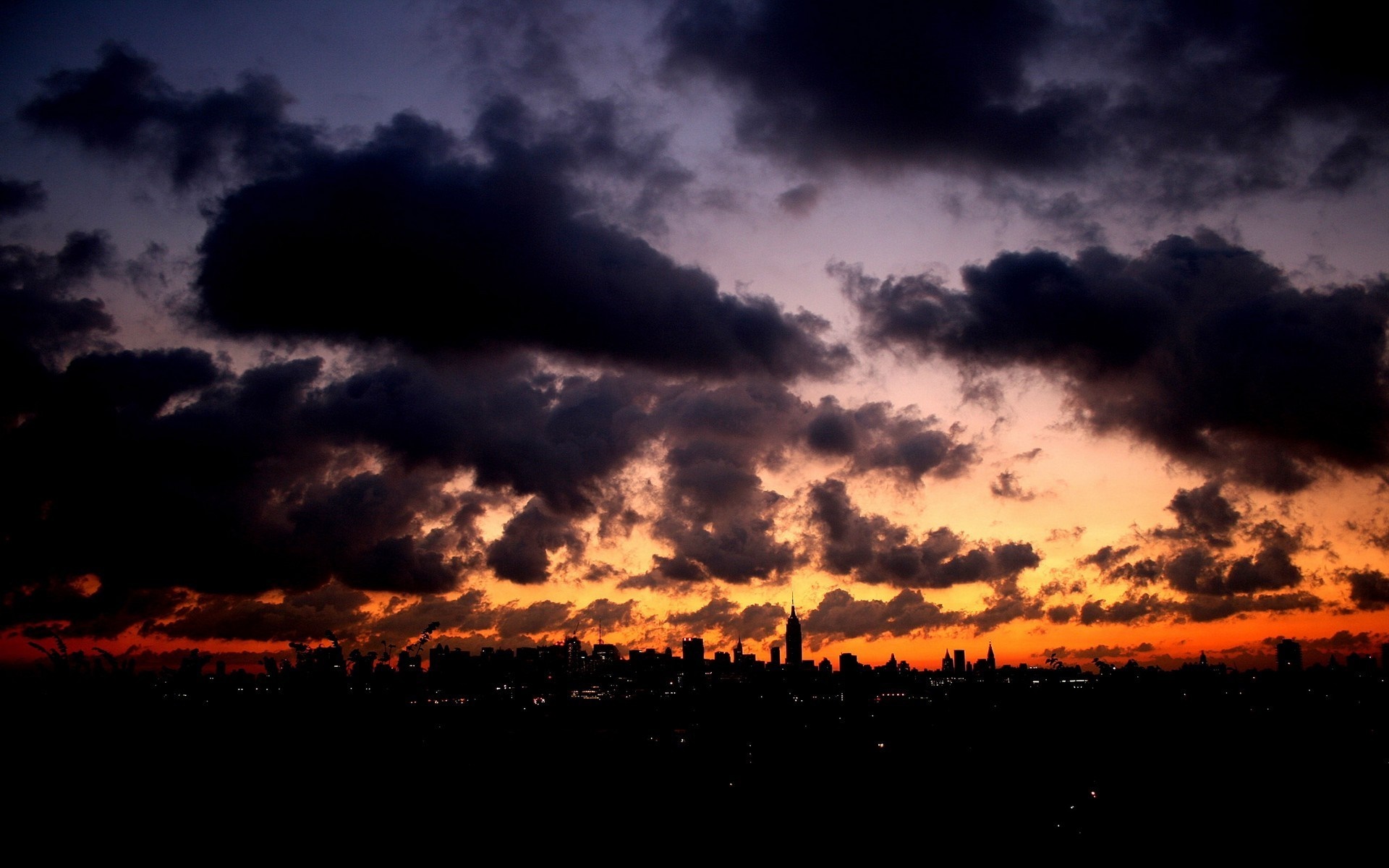 Cityscape at sunset with dark clouds HD Wallpaper