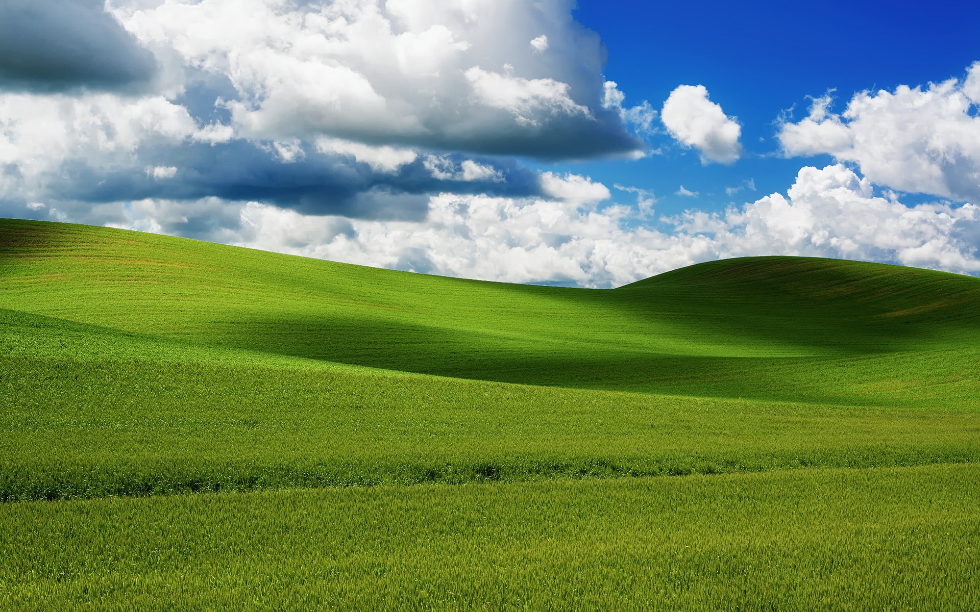 Rolling green hills under a cloudy blue sky HD Wallpaper