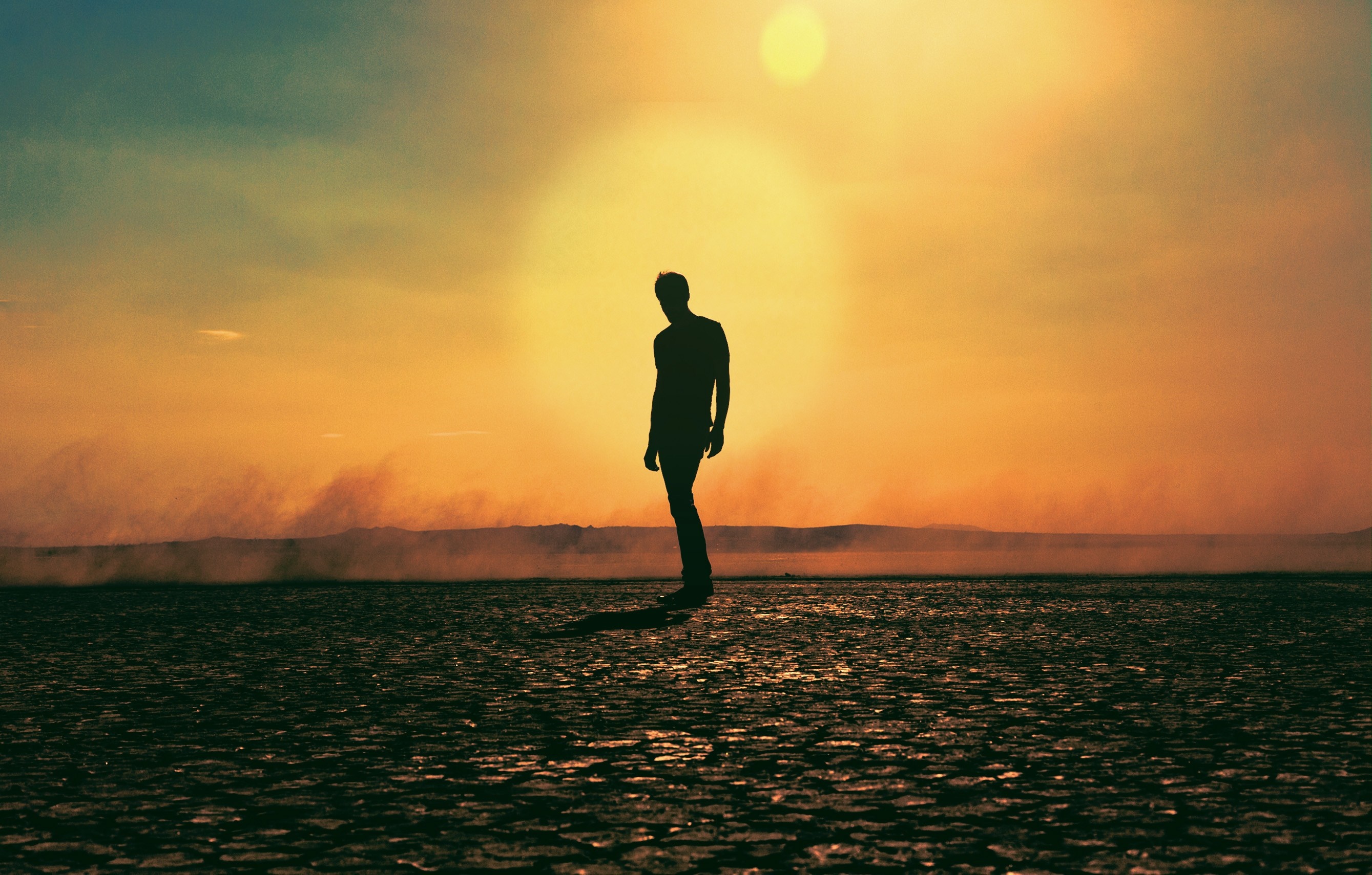 Silhouette of a man against a sunset over a dry landscape HD Wallpaper