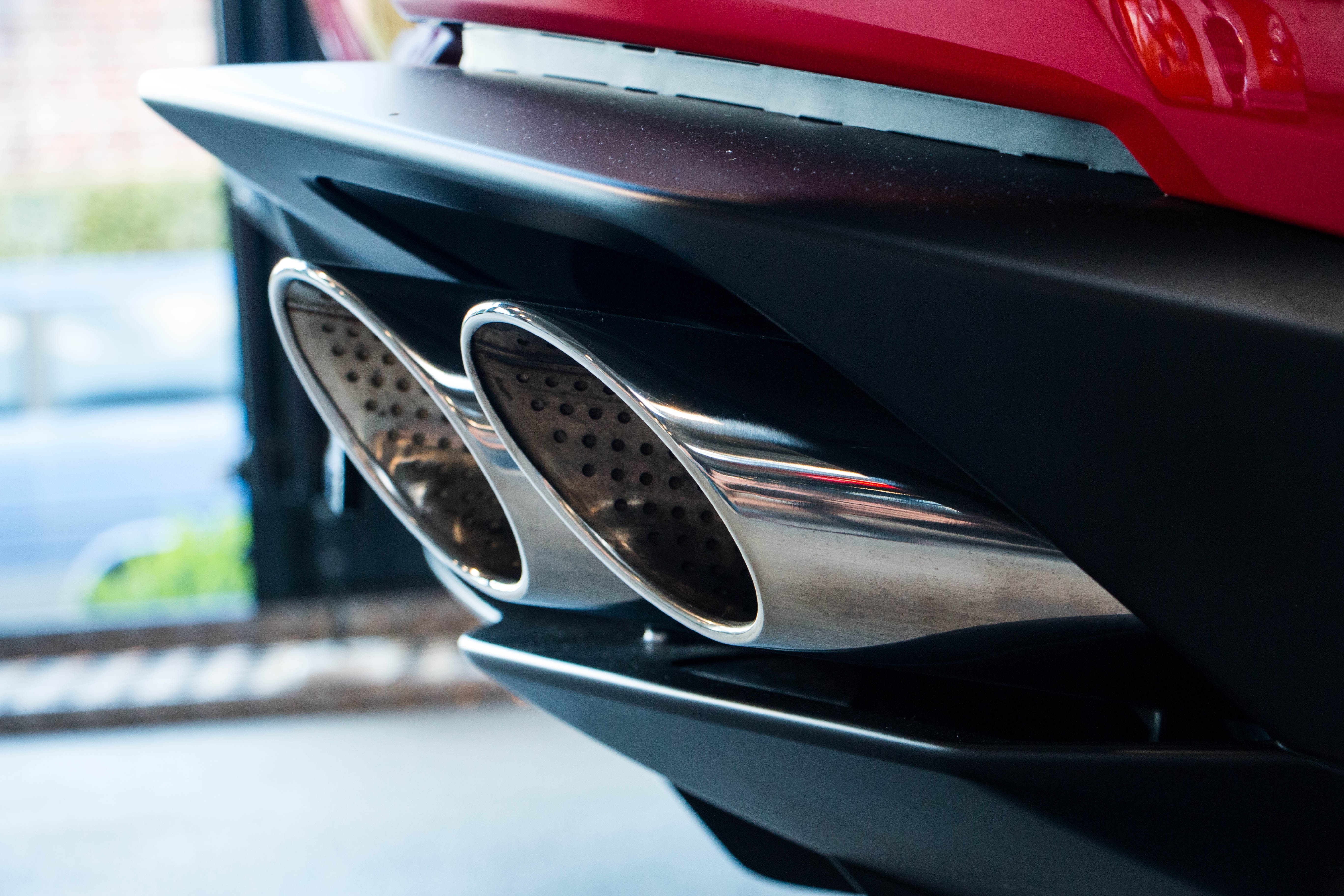 Close-up of a red sports car's dual exhaust pipes HD Wallpaper