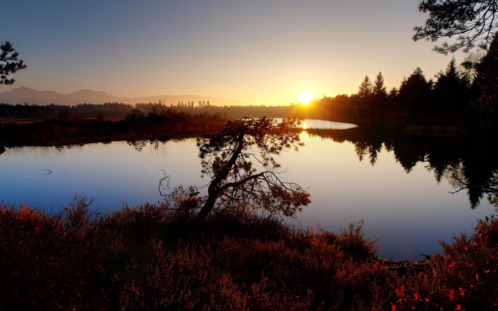 Sunset over a calm lake with trees and mountains HD Wallpaper