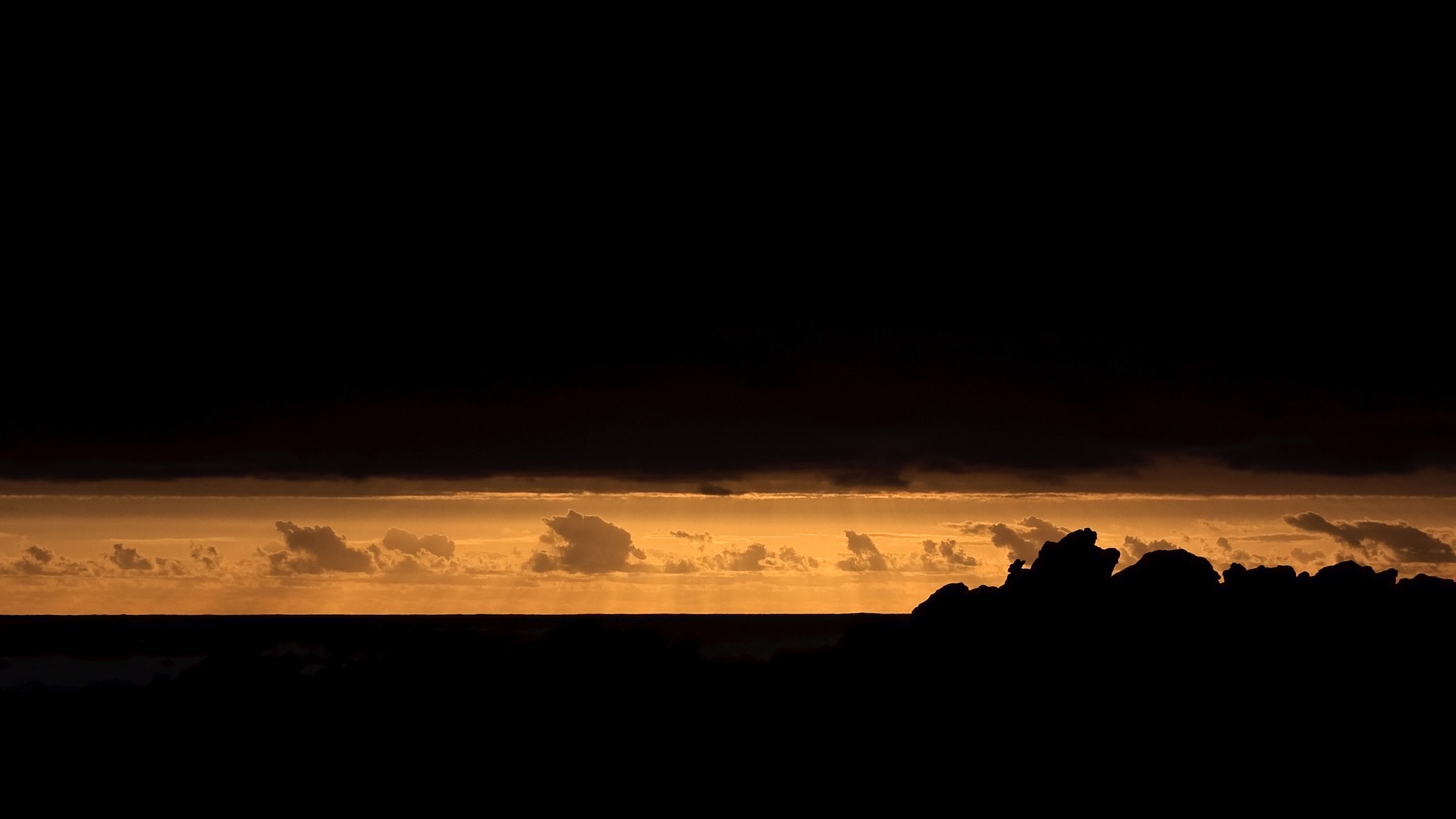 Silhouette of rocks against a sunset sky HD Wallpaper