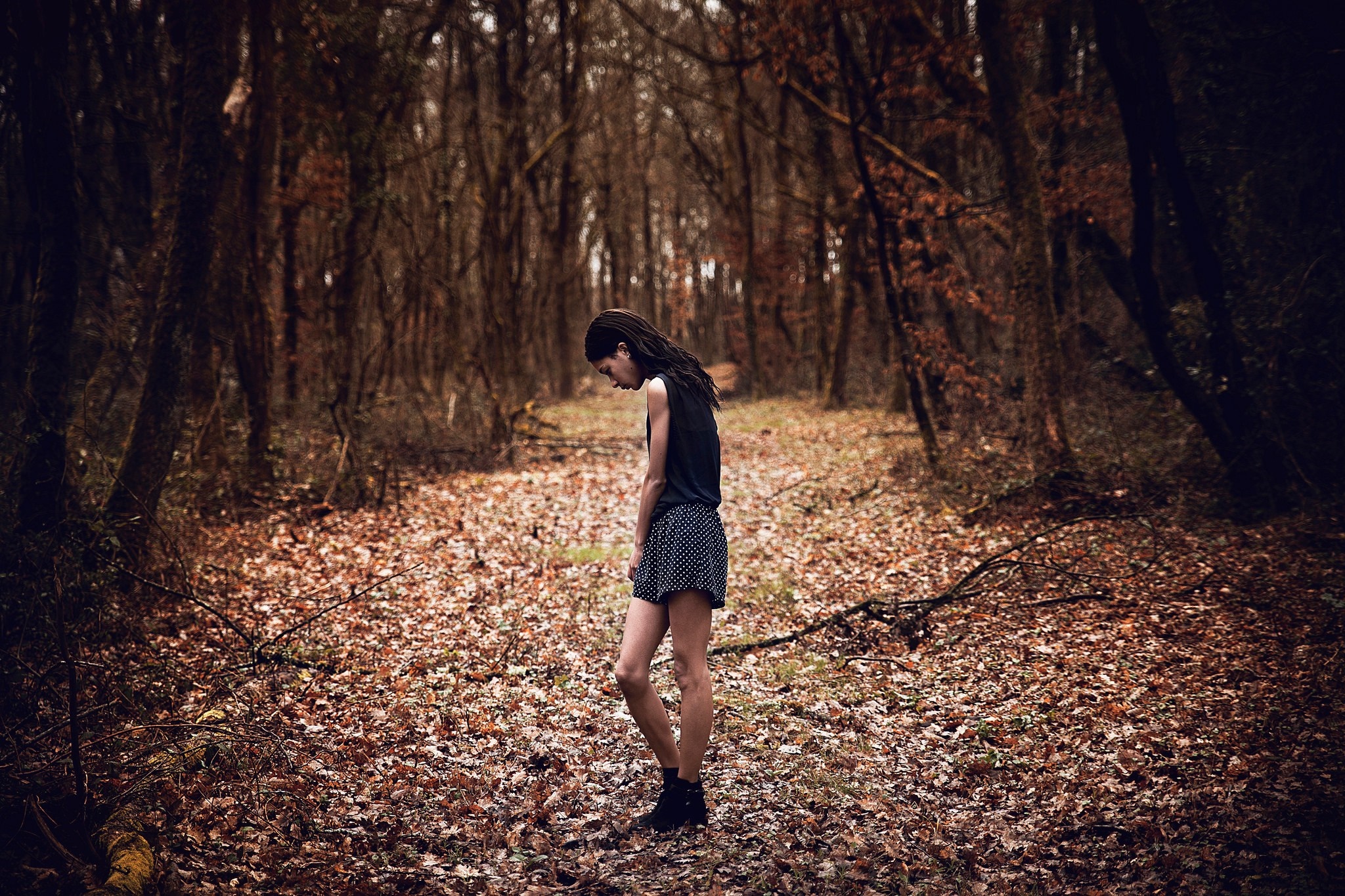 Woman in a dark forest with fallen leaves HD Wallpaper