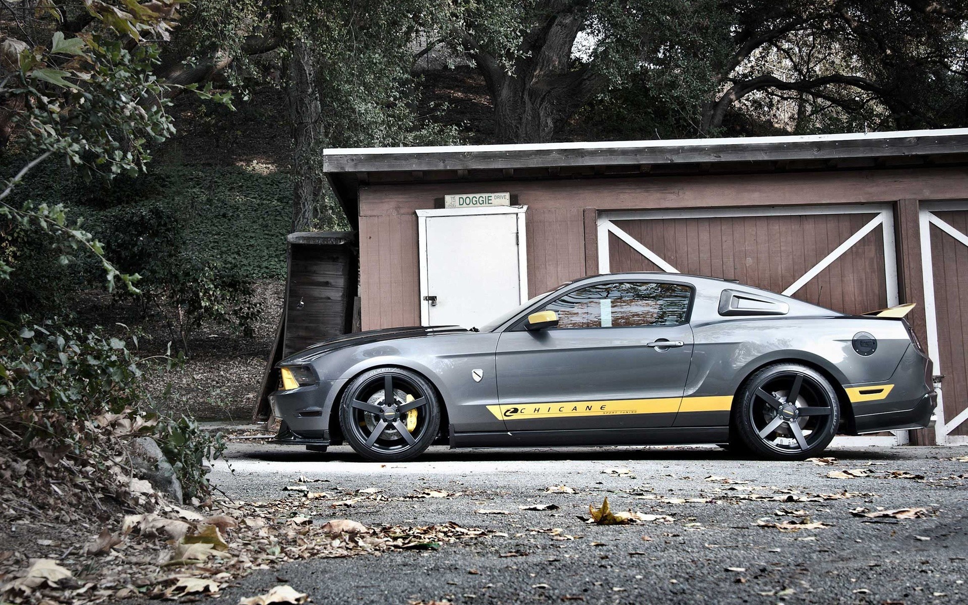 Gray Ford Mustang with yellow accents parked by a shed HD Wallpaper