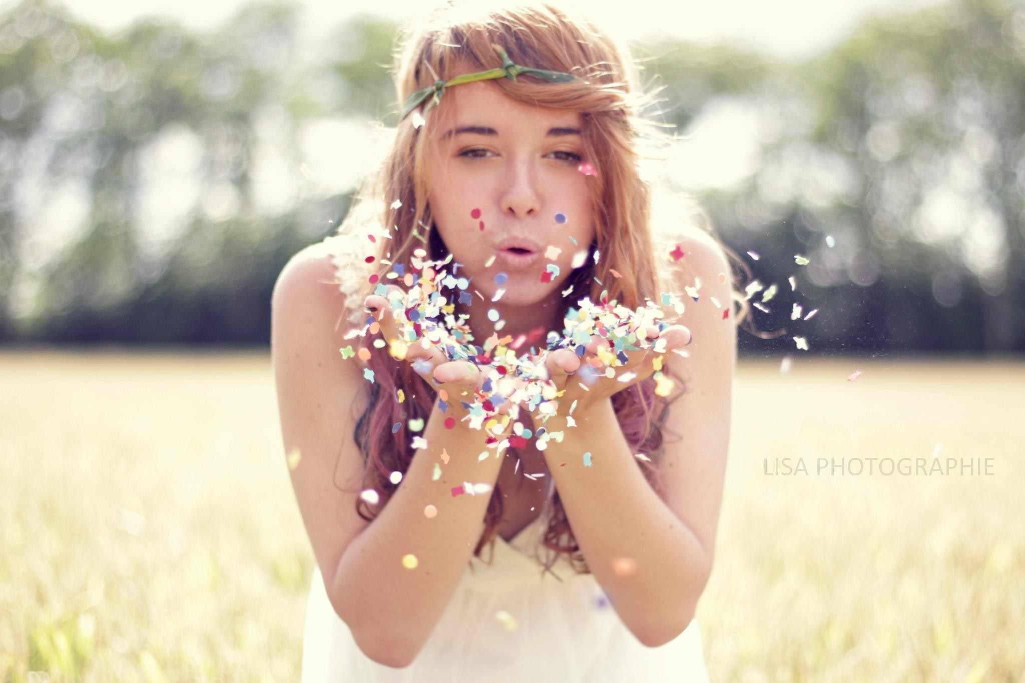 Woman blowing confetti in a field HD Wallpaper