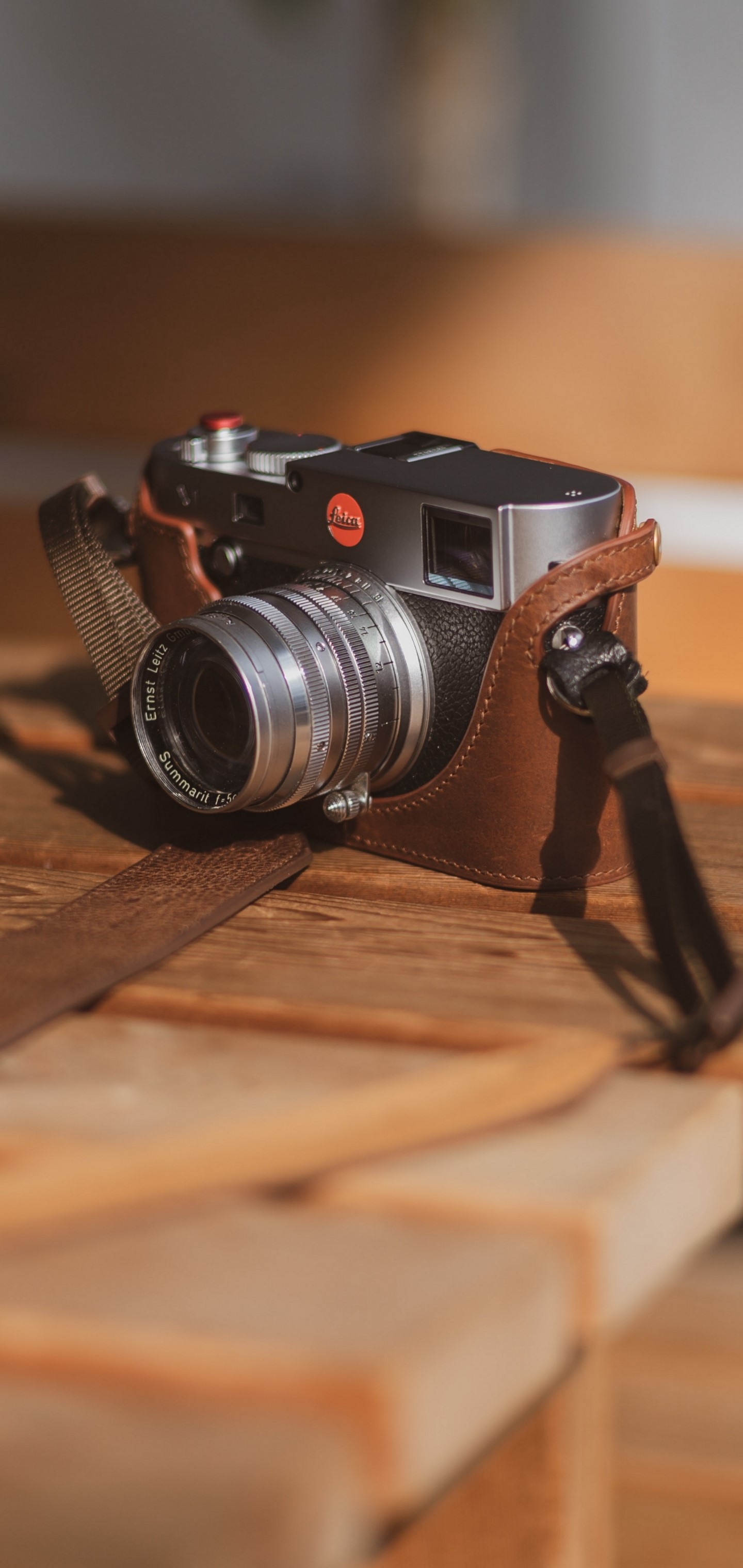 Leica camera with leather case on wooden table HD Phone Wallpaper