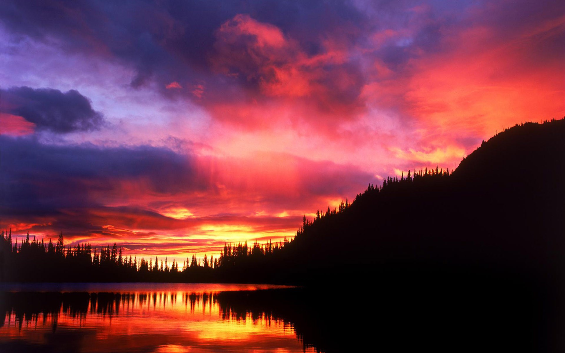Sunset over a lake with silhouetted trees and mountains HD Wallpaper