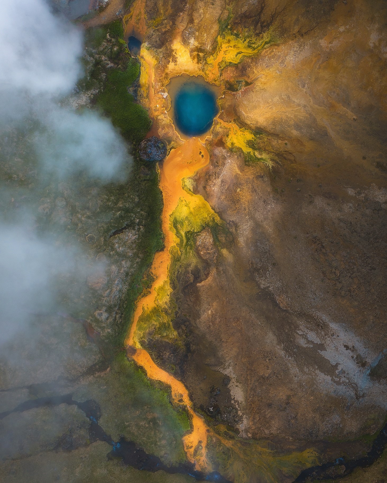 Aerial view of a geothermal pool with colorful mineral deposits HD Phone Wallpaper